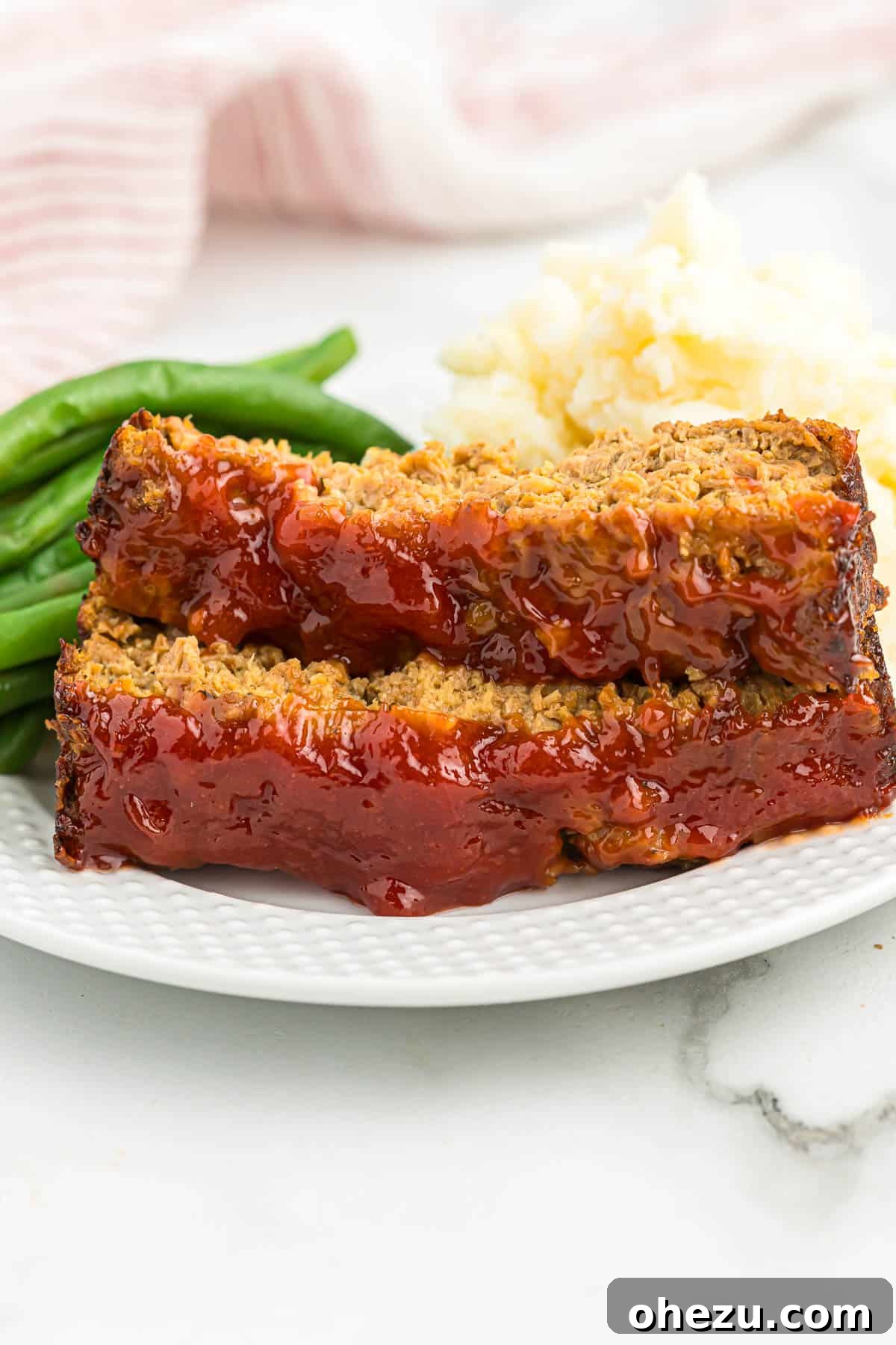 Meatless Meatloaf Marvel 2 Delicious vegetarian meatloaf served with vibrant green beans and creamy mashed potatoes on a white plate, ready for a comforting family meal.