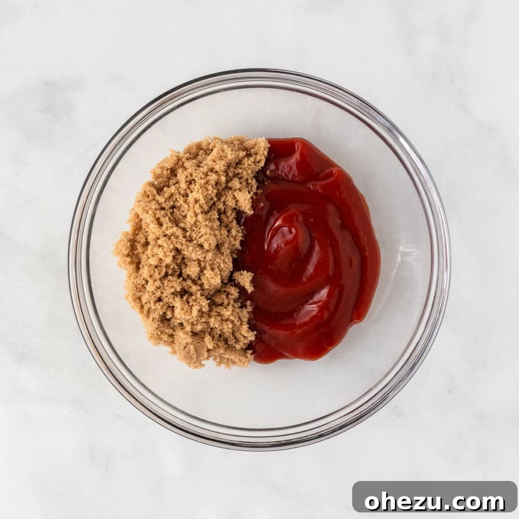 Meatless Meatloaf Marvel 12 A small bowl holding a vibrant red base of ketchup, with a scoop of dark brown sugar poised to be mixed in for the sweet and tangy meatloaf glaze.