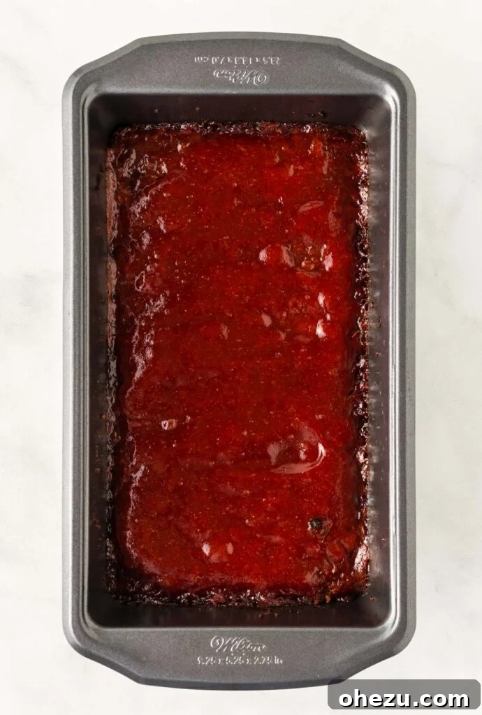 Meatless Meatloaf Marvel 15 The fully baked vegetarian meatloaf in its loaf pan, featuring a beautifully caramelized, bubbly ketchup and brown sugar glaze on top, with browned edges, indicating it's perfectly cooked.