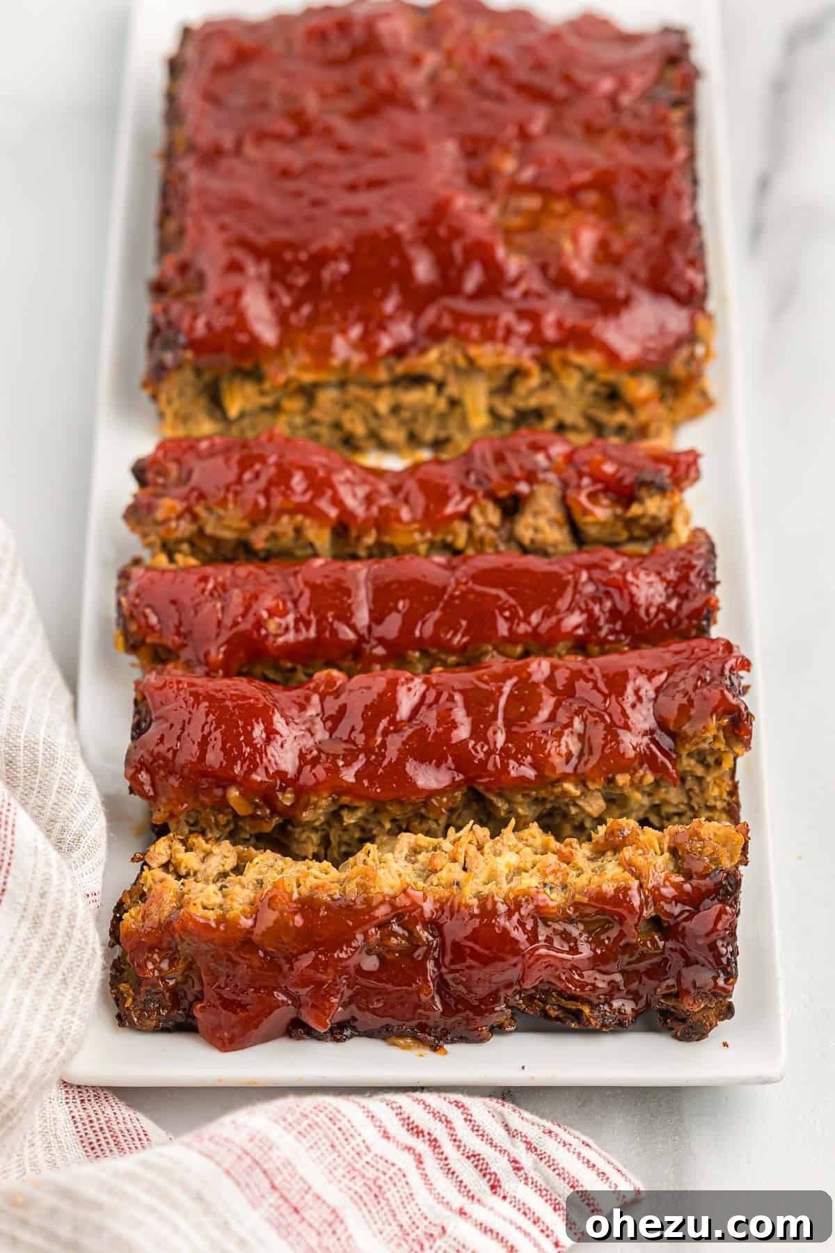 Meatless Meatloaf Marvel 17 Two generous slices of vegetarian meatloaf on a white plate, showcasing the browned glaze and appealing texture, ready for a satisfying meal.