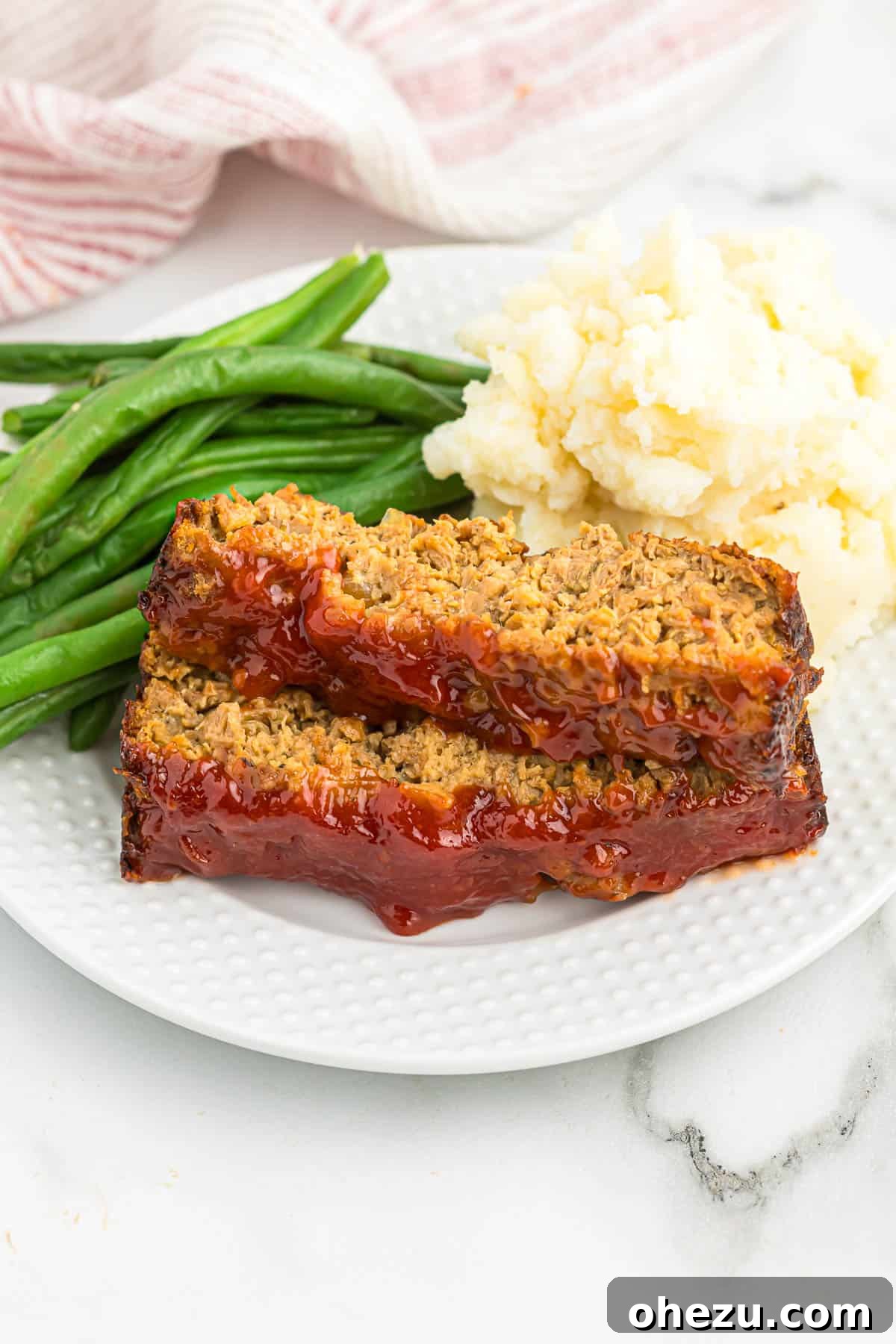 Meatless Meatloaf Marvel 3 A warm, freshly baked vegetarian meatloaf, sliced and ready to serve, accompanied by a side of mashed potatoes and vibrant green beans.