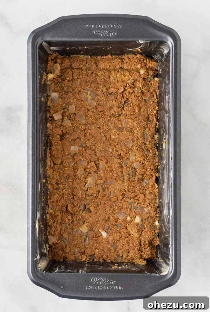 Meatless Meatloaf Marvel 10 Raw vegetarian meatloaf mixture neatly pressed into a greased loaf pan, ready for the oven, displaying a smooth and even surface.