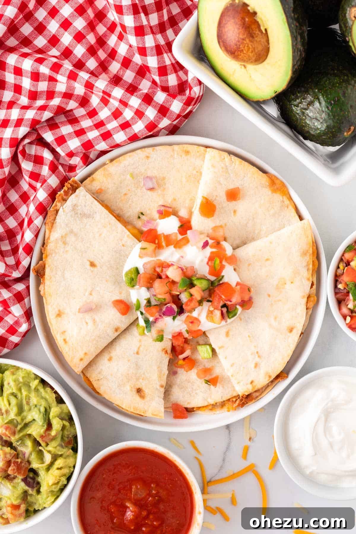 Crispy air fryer quesadillas on a plate, topped with fresh sour cream and vibrant pico de gallo.