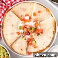 quesadillas on a plate topped with sour cream and pico