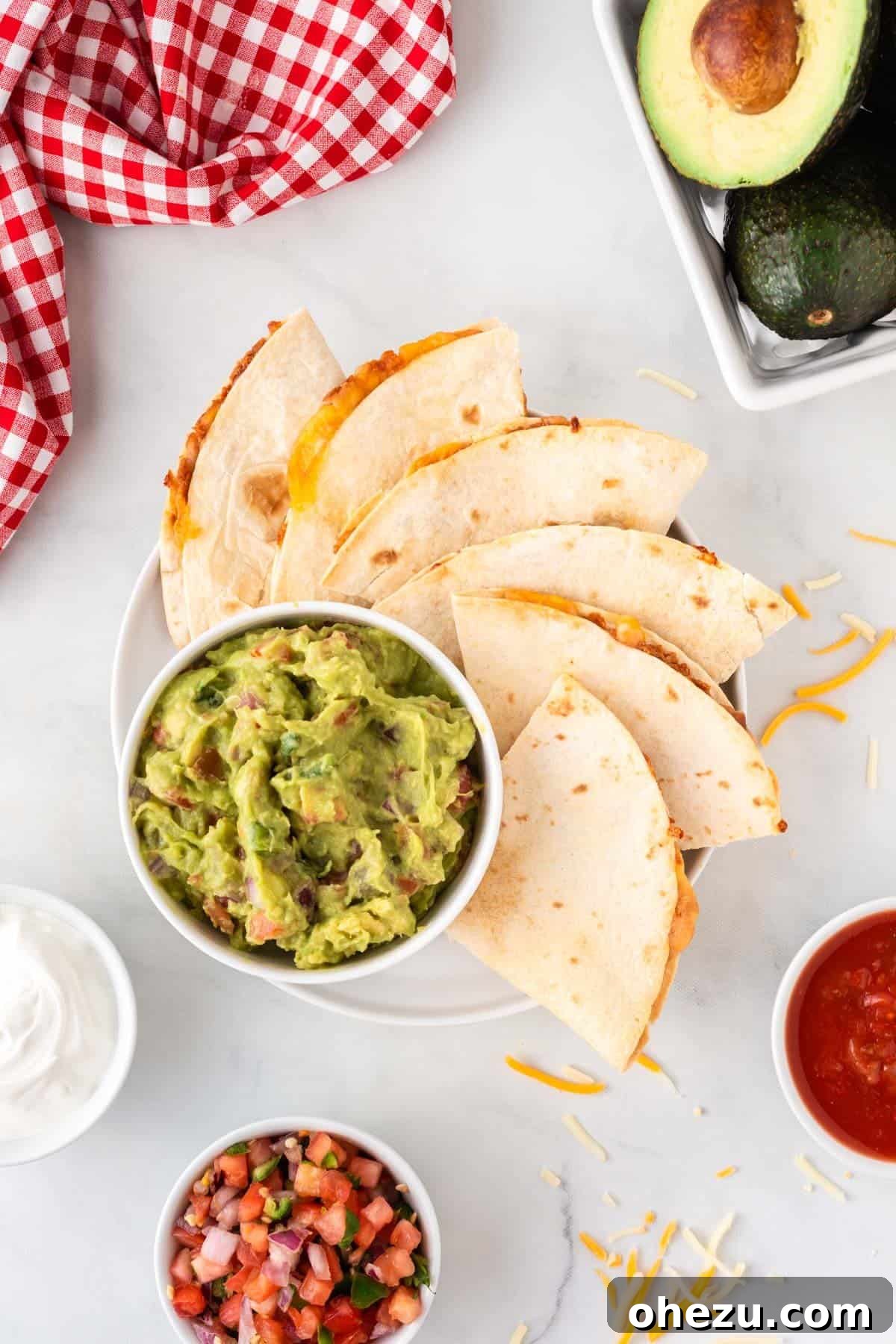 A plate featuring perfectly air-fried quesadilla wedges alongside a bowl of fresh guacamole, ready for dipping.