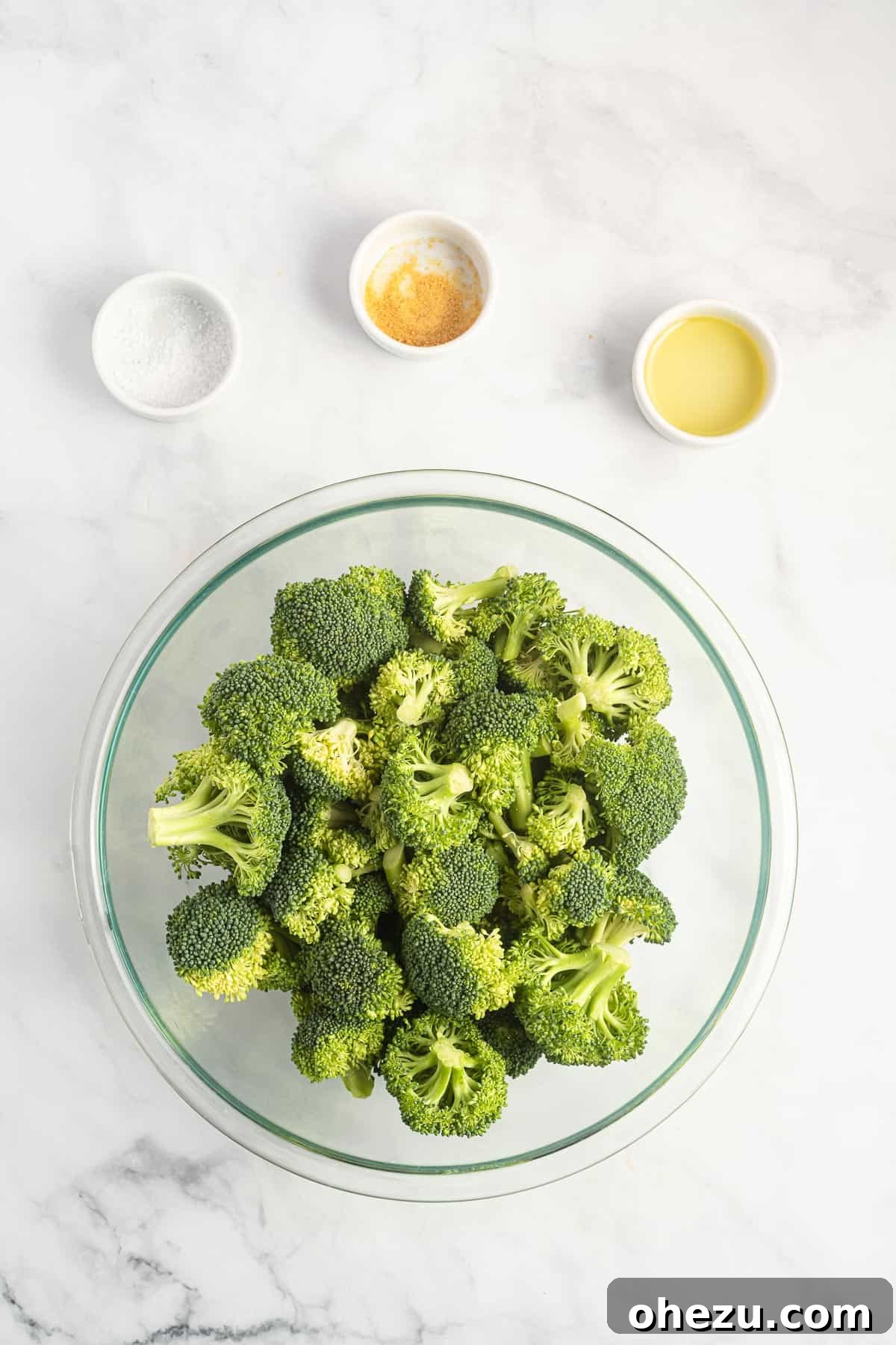 broccoli florets in a bowl surrounded by the spices