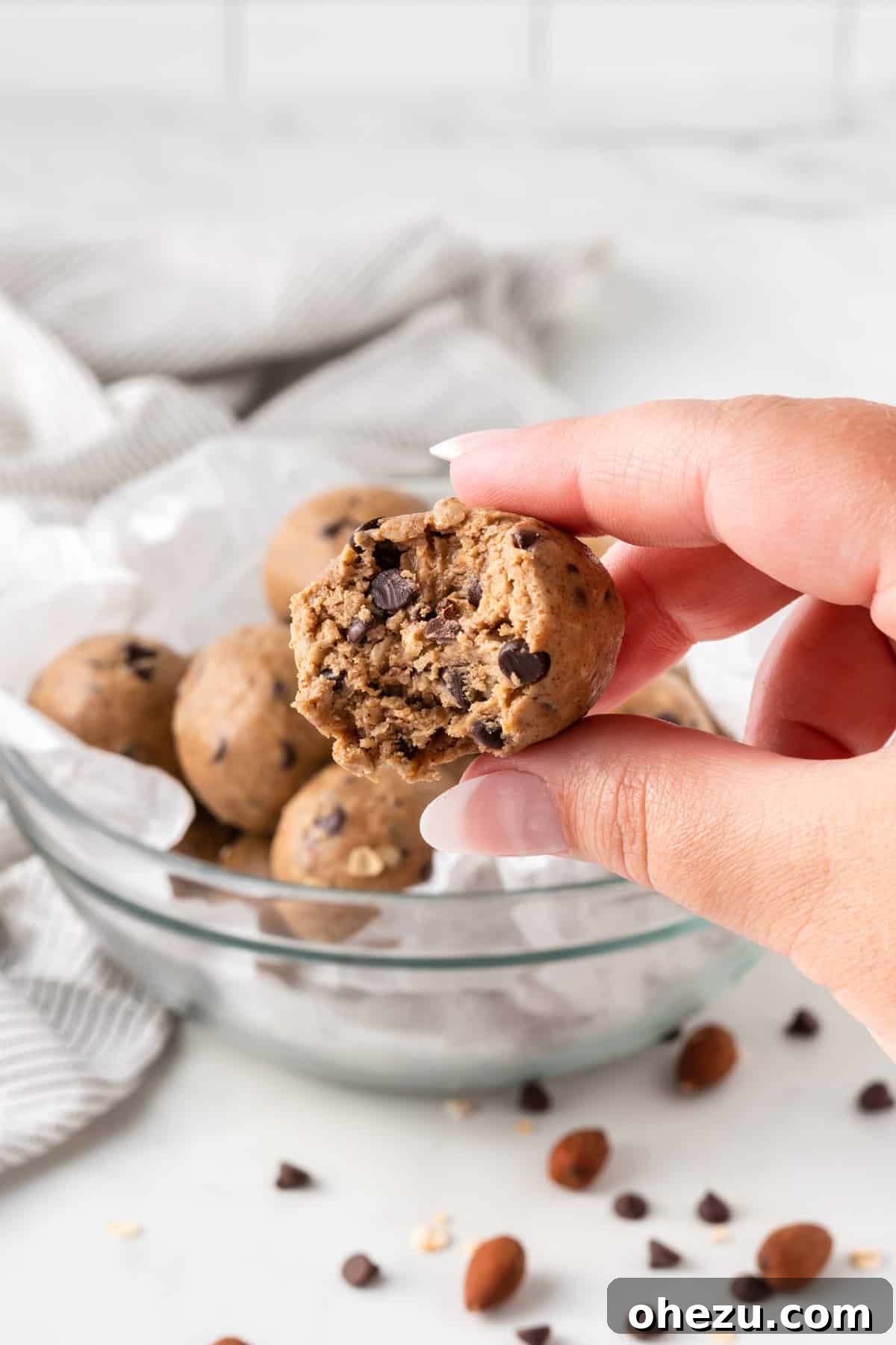 Wholesome Almond Butter Protein Bites 10 A close-up of an almond butter protein ball with a bite taken out, revealing its rich, chewy texture and the dispersed mini chocolate chips and oats inside, tempting the viewer.