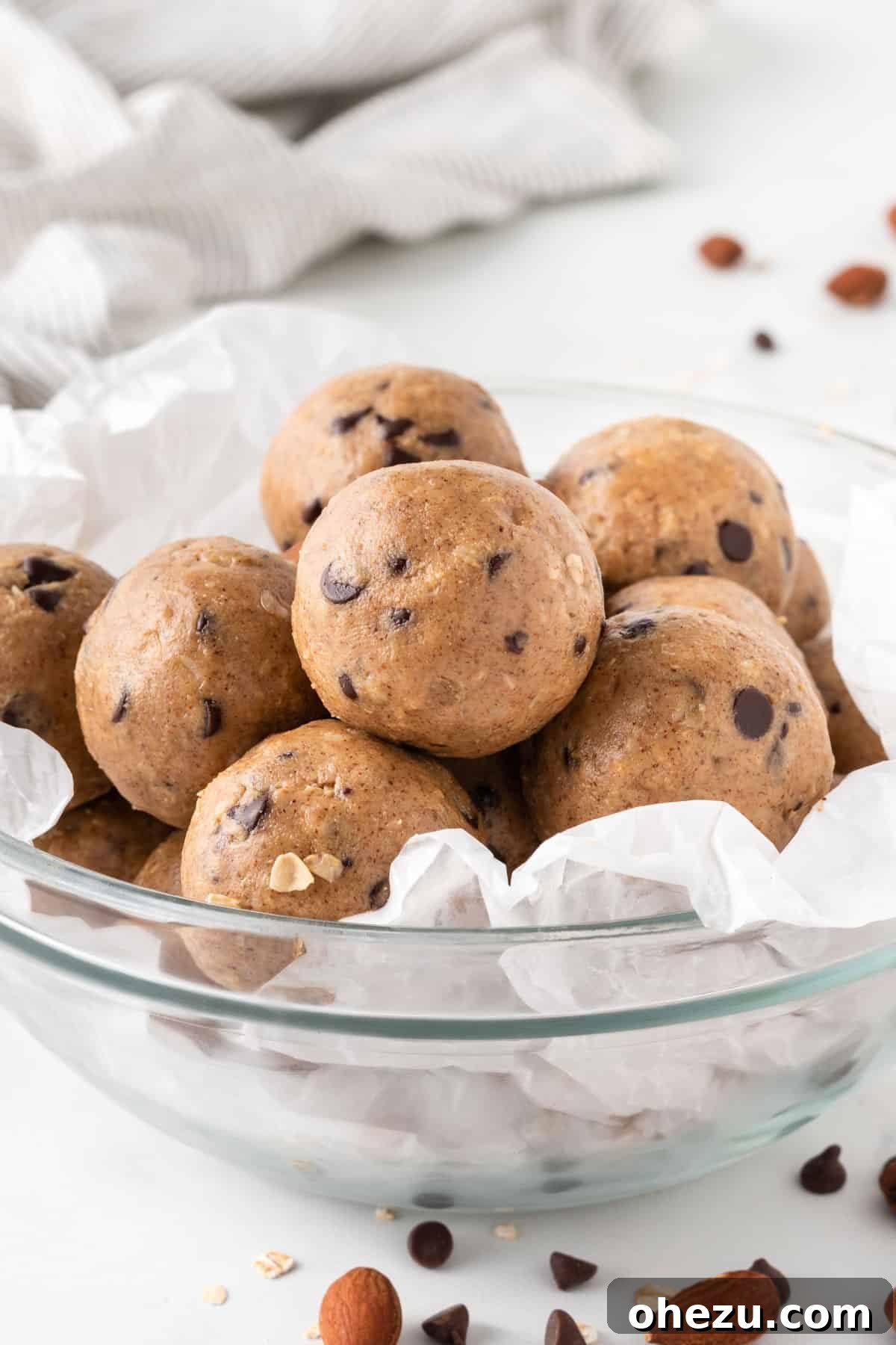 Wholesome Almond Butter Protein Bites 11 A large, inviting stack of perfectly shaped almond butter protein balls in a white bowl, against a light background, showcasing their deliciousness.