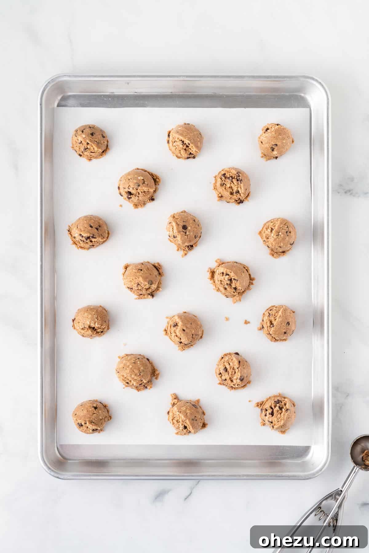 Wholesome Almond Butter Protein Bites 7 Evenly spaced scoops of almond butter energy ball batter resting on a parchment paper-lined baking sheet, awaiting their chilling time.