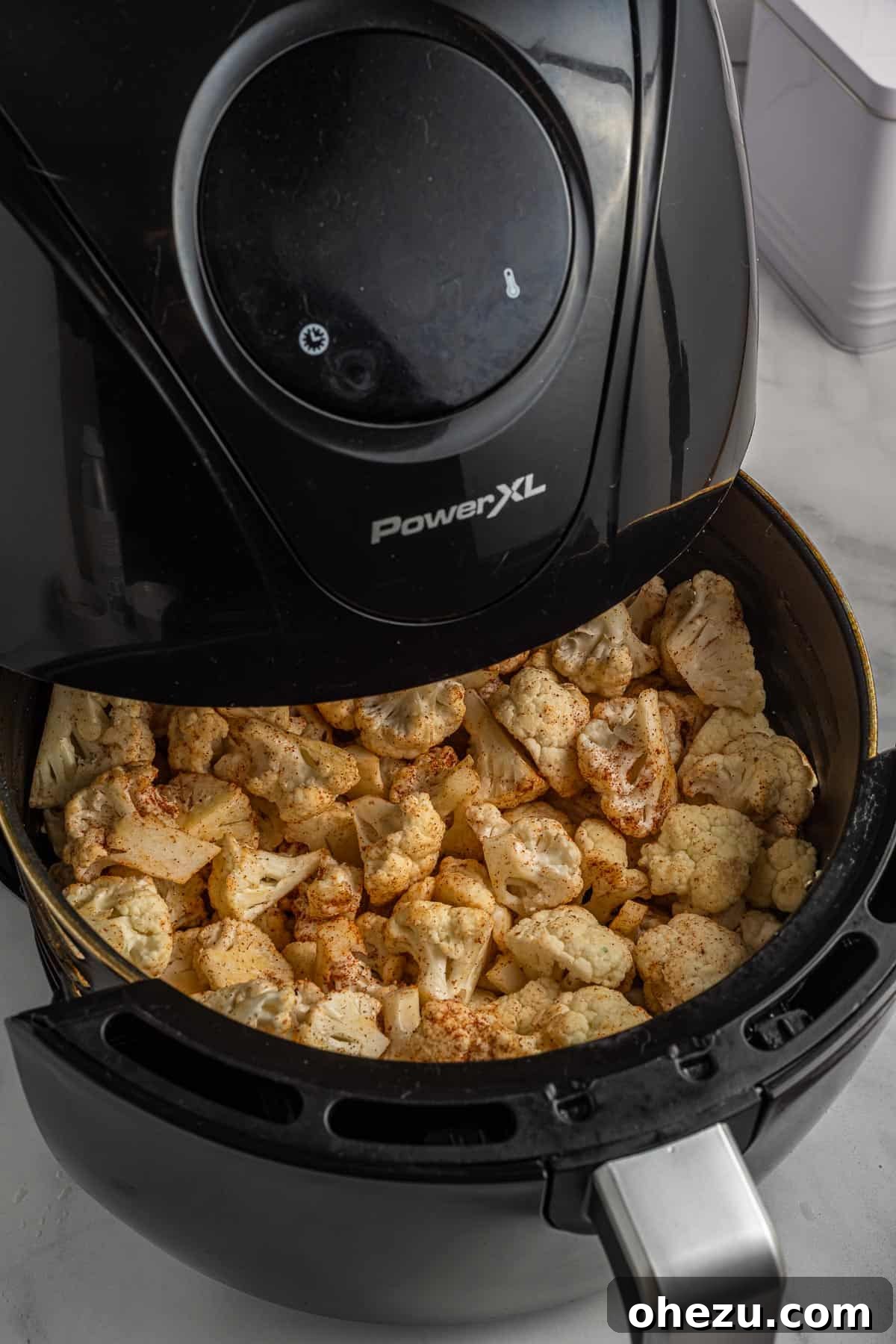Crispy, golden-brown air-fried cauliflower florets shown inside the air fryer basket.
