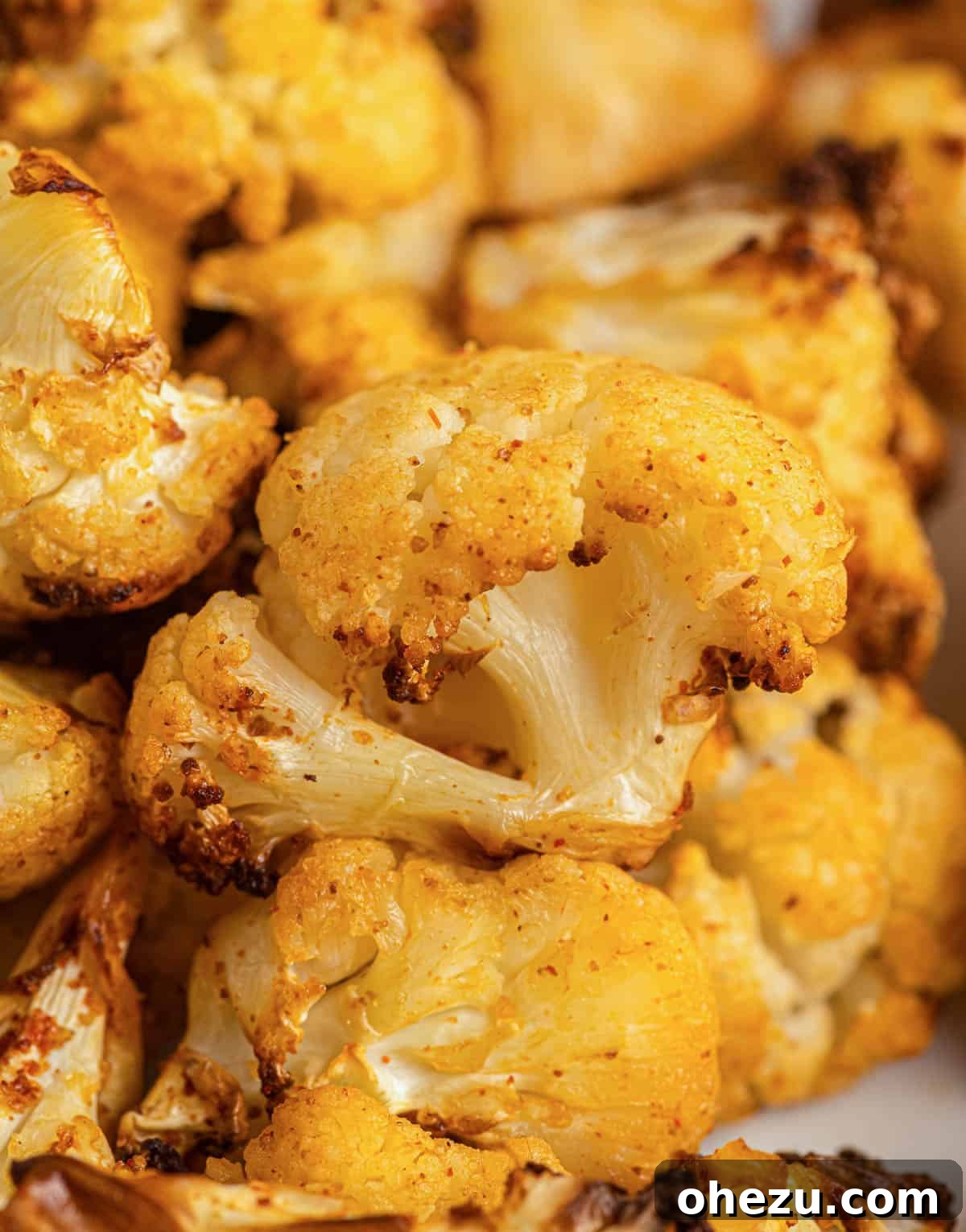 A close-up texture shot of a single crispy air fryer cauliflower floret, showing its golden-brown exterior and tender interior.