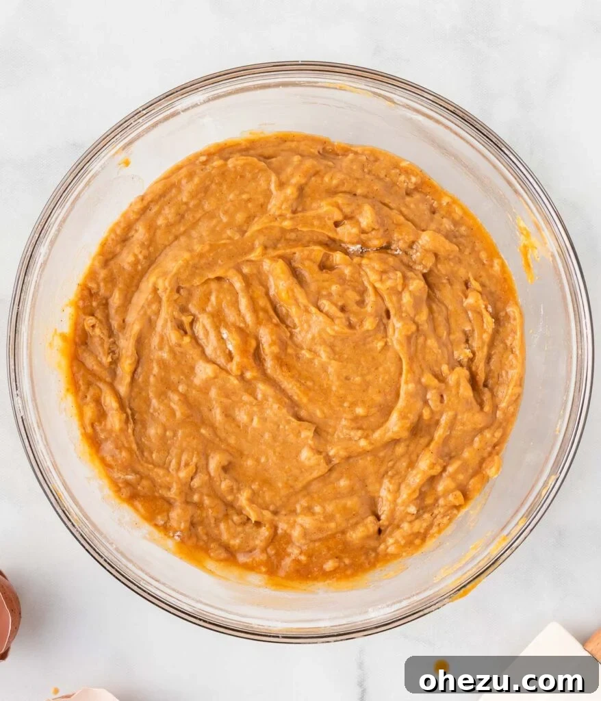 A bowl of freshly mixed pumpkin muffin batter, showcasing its smooth, slightly lumpy texture, ready for the next step.
