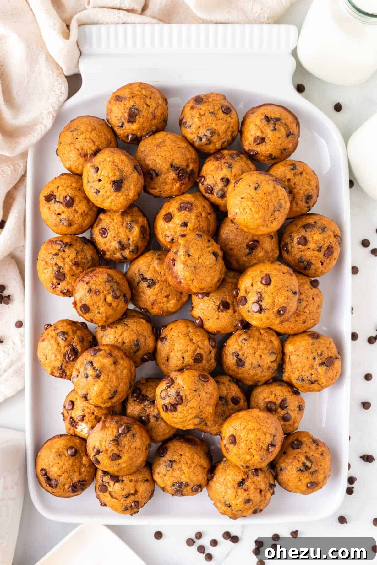 A beautiful arrangement of golden pumpkin mini muffins artfully placed on a white platter, inviting viewers to indulge.