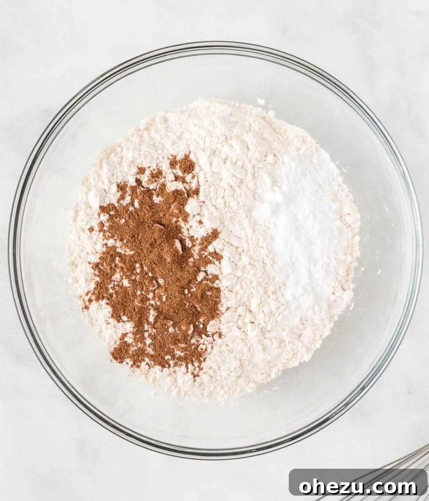 A mixing bowl containing a pristine white mound of dry ingredients like flour and baking soda, ready for whisking.