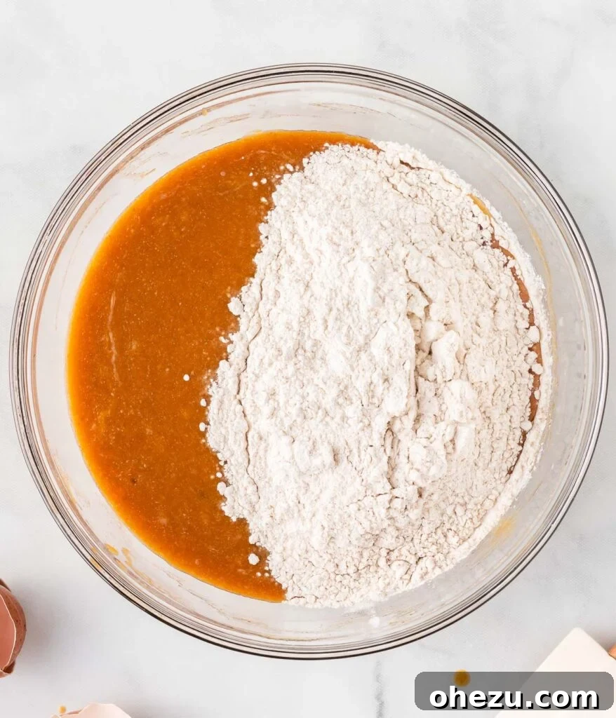 The dry ingredients are carefully being added to the bowl containing the wet ingredients, preparing for gentle mixing.