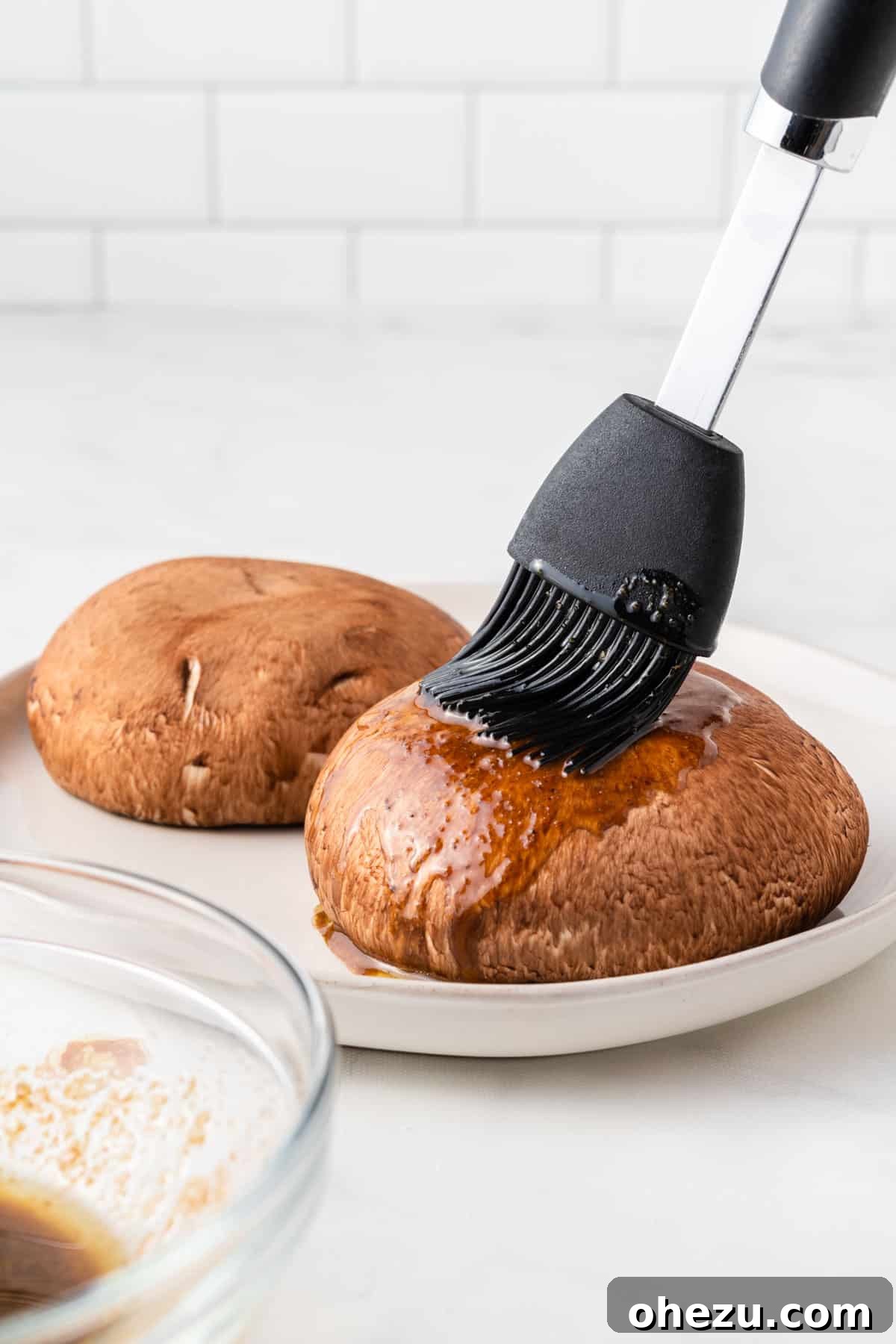 Perfect Air Fryer Portobello 5 using a basting brush to cover the mushrooms in liquid