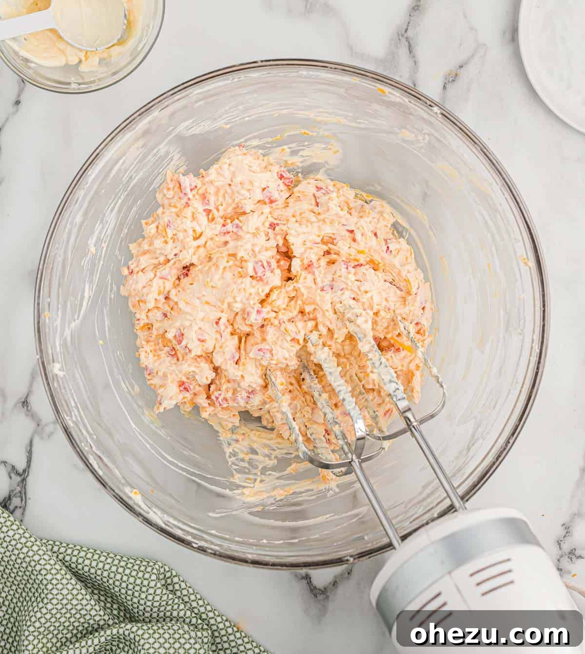 mixing the pimento cheese in a glass bowl