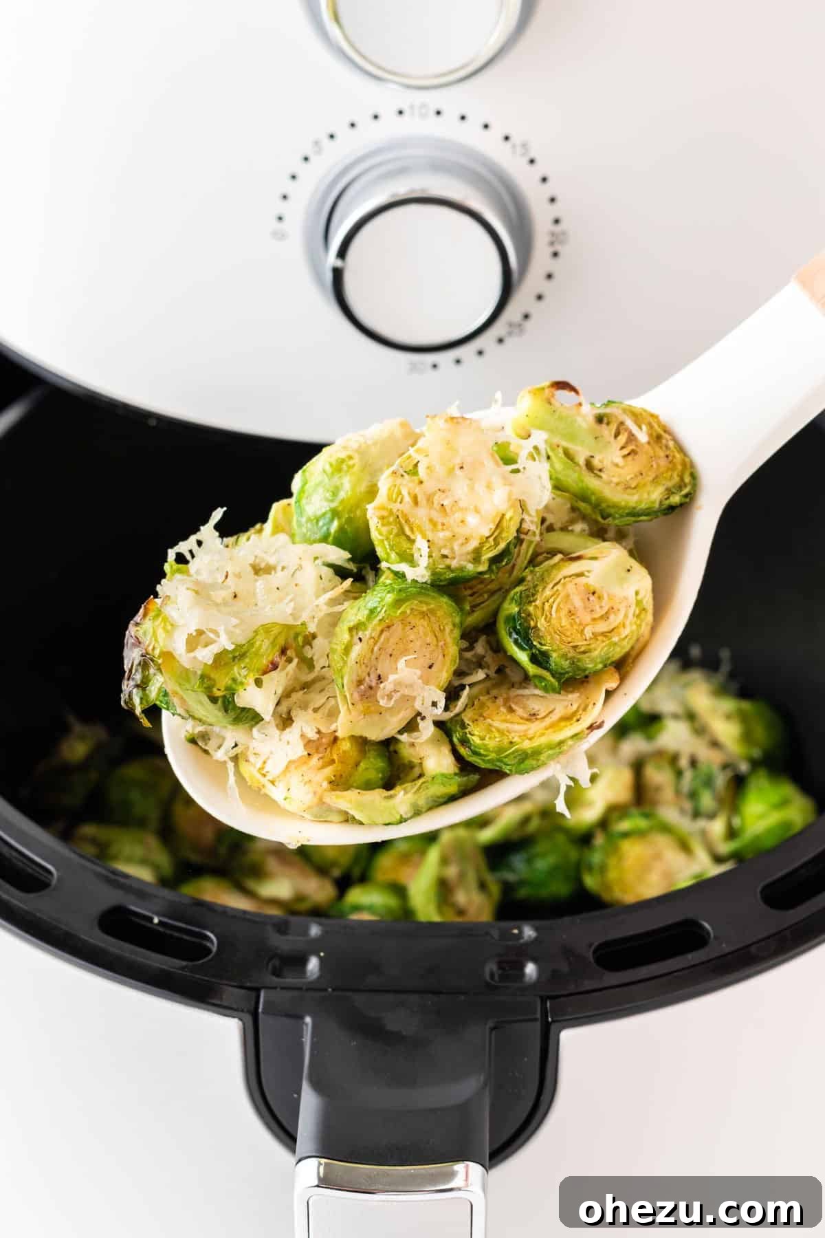 Perfectly Crispy Air Fryer Brussels Sprouts 11 Spoon lifting a scoop of cheesy air-fried Brussels sprouts, showing the melted Parmesan