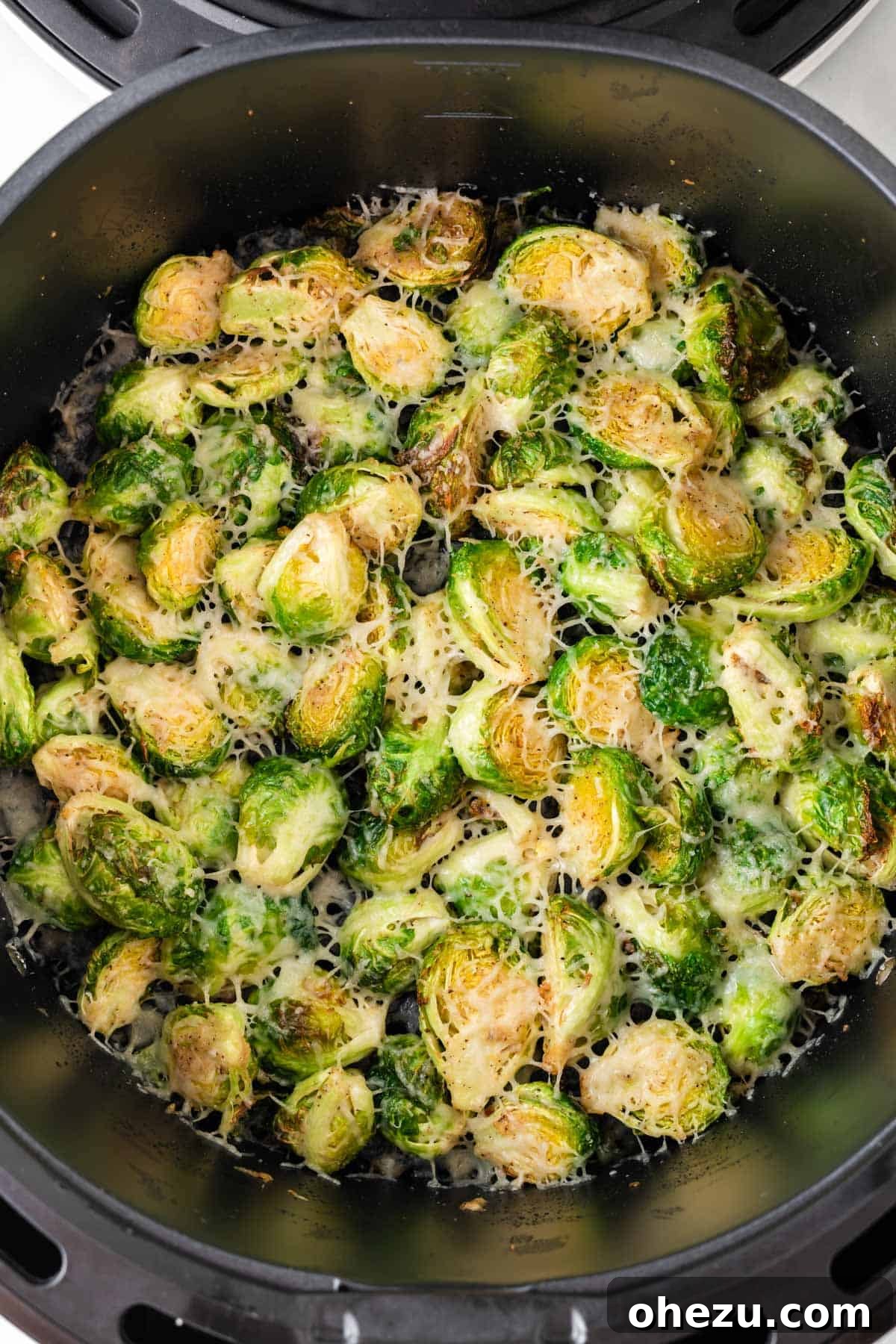 Perfectly Crispy Air Fryer Brussels Sprouts 12 A close-up of crispy Brussels sprouts with melted cheese in the air fryer basket