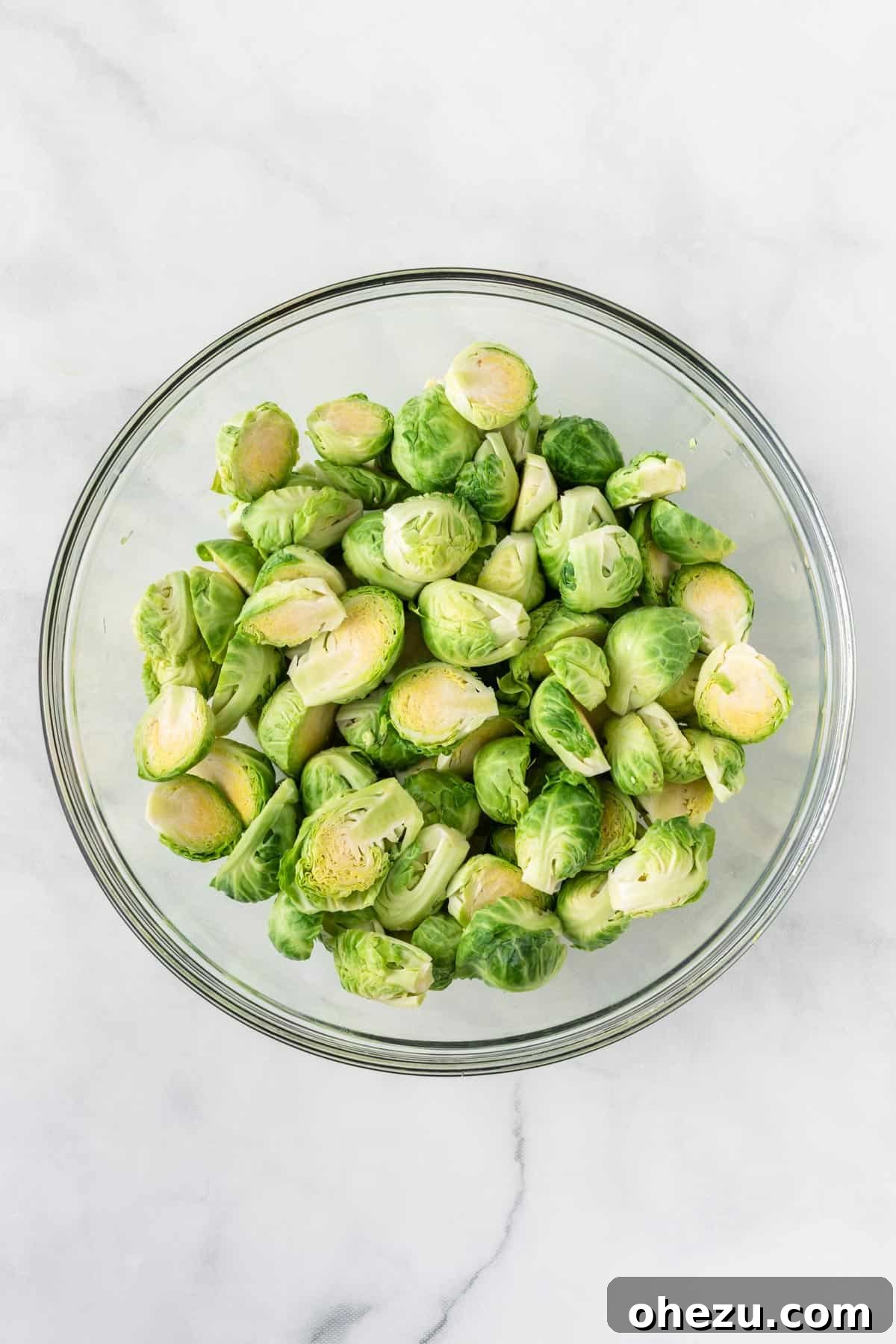 Perfectly Crispy Air Fryer Brussels Sprouts 5 Halved Brussels sprouts in a clear glass mixing bowl