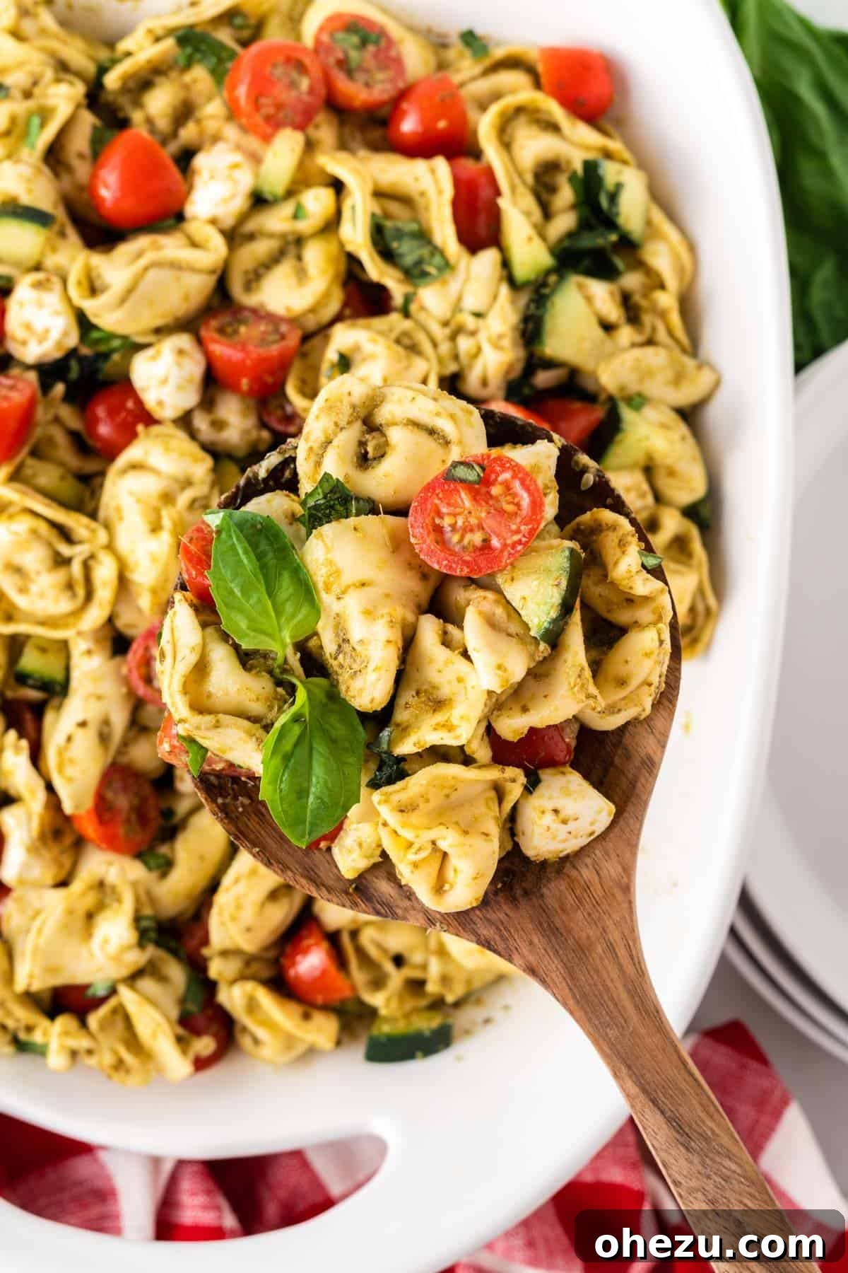 Flavorful Tortellini Pasta Salad 3 serving tortellini pasta salad with a wooden spoon