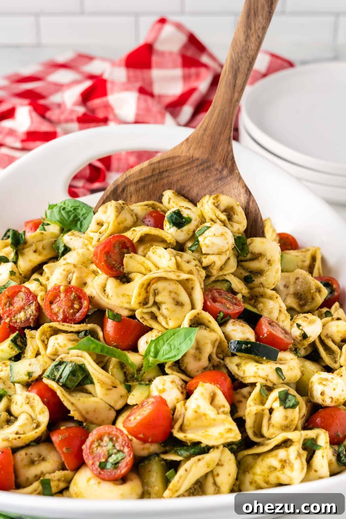 Flavorful Tortellini Pasta Salad 9 serving tortellini pasta salad with a wooden spoon
