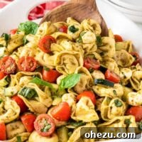 serving tortellini pasta salad with a wooden spoon
