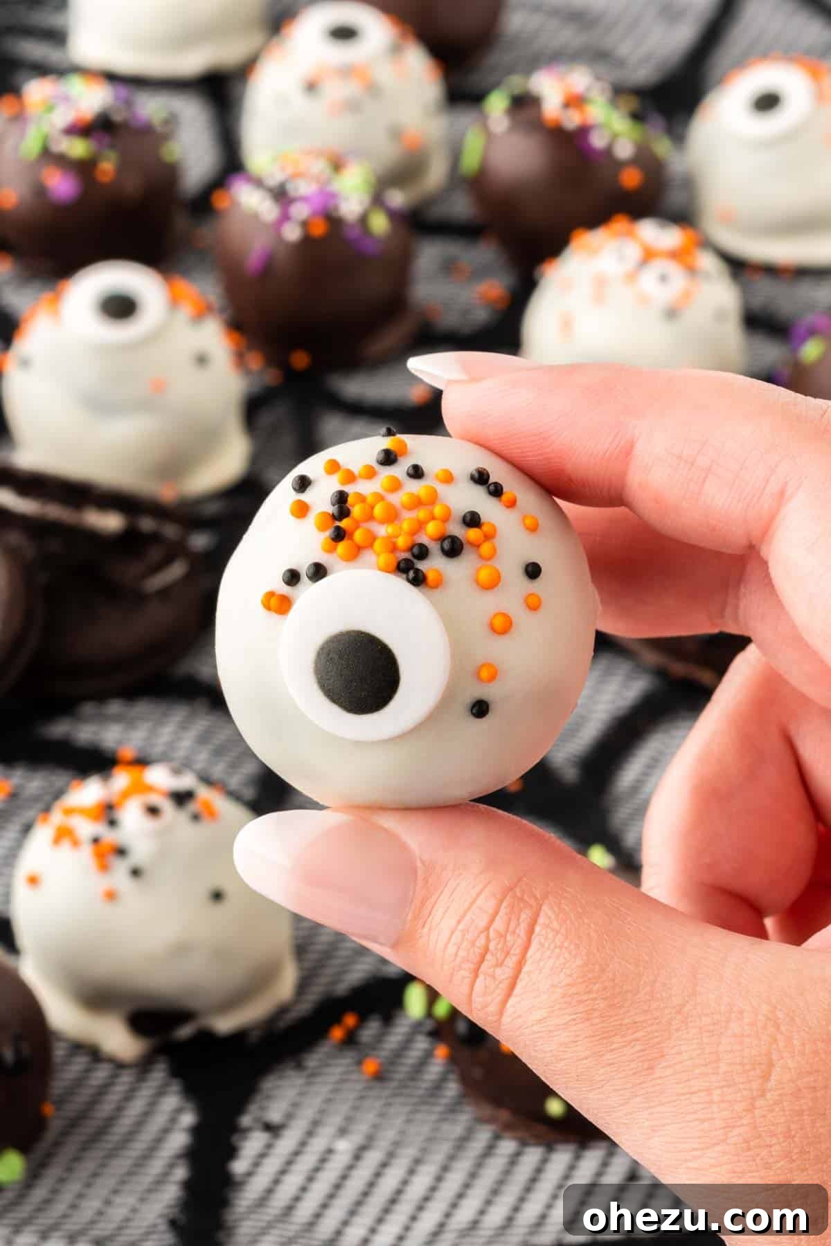 Wicked Oreo Truffles 18 A hand gently holding a decorated Oreo ball, showing its appealing texture