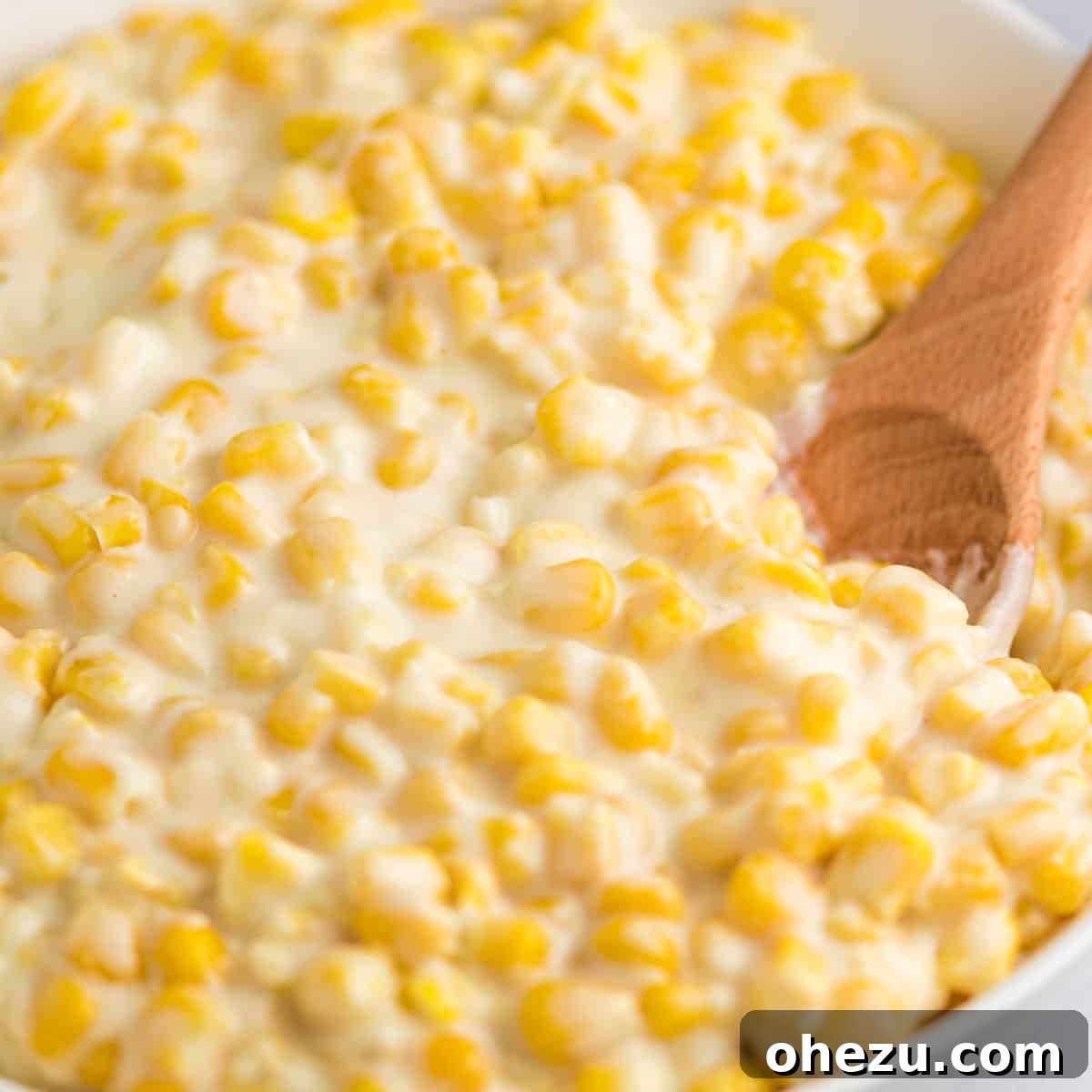 Overhead shot of a bowl of slow cooker creamed corn, garnished with fresh herbs, ready to be enjoyed as a comforting side.