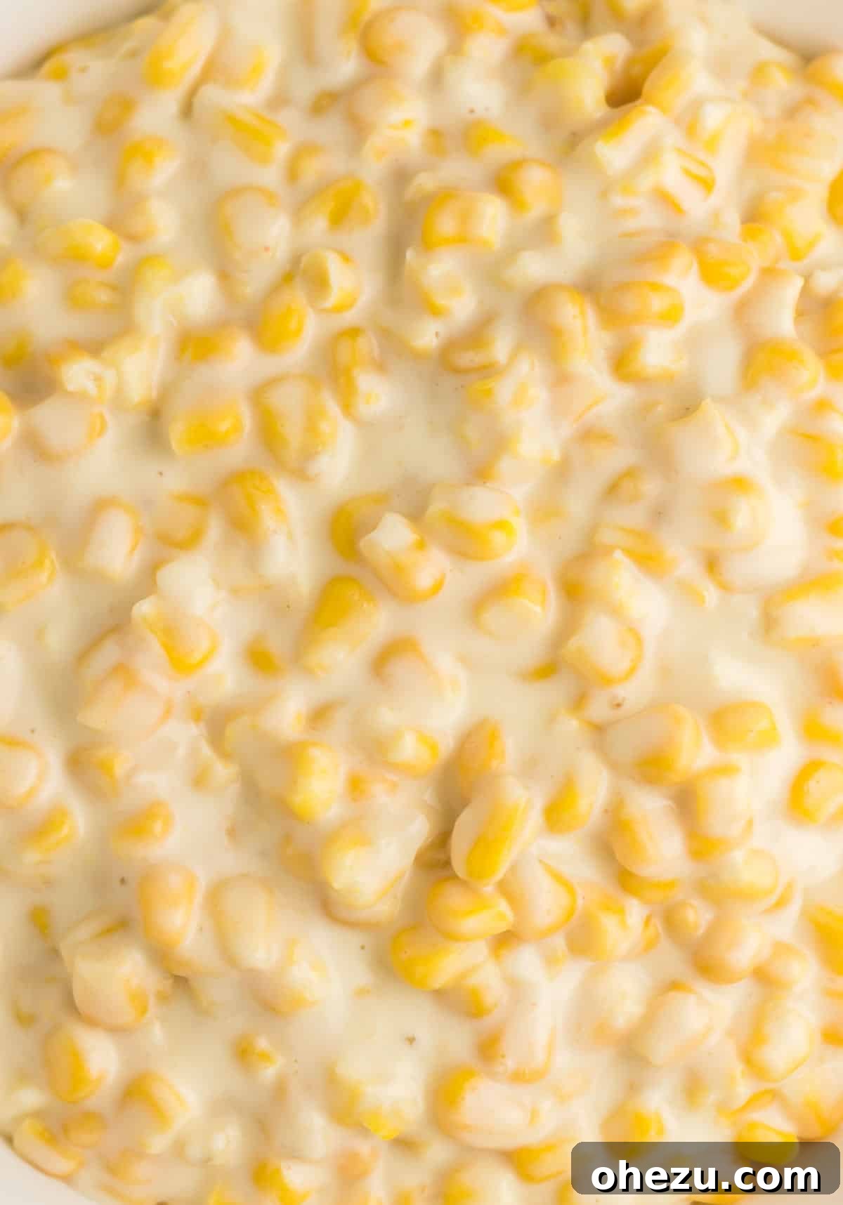 A close-up shot of rich and cheesy slow cooker creamed corn, garnished with fresh herbs, showcasing its irresistible texture.