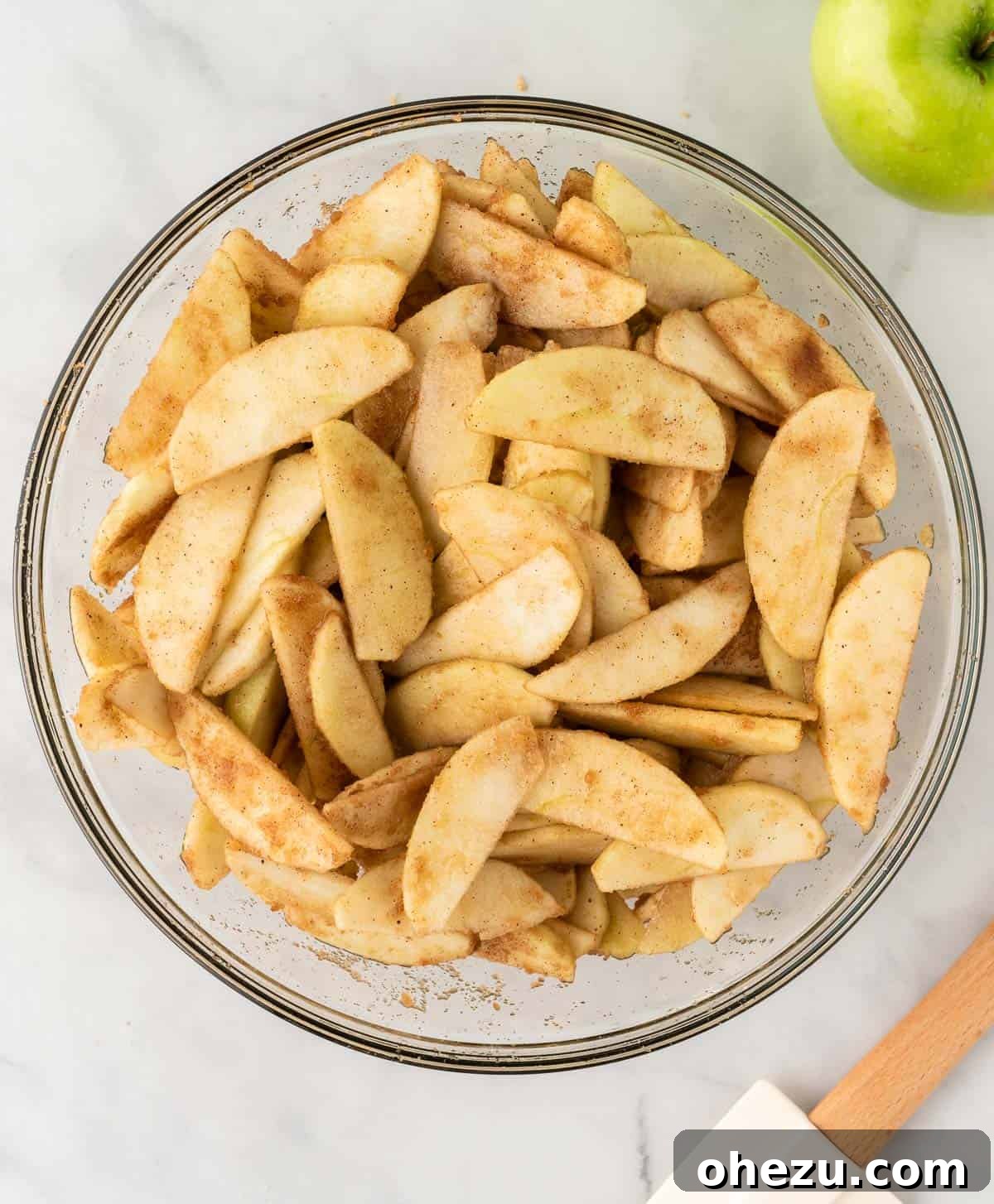 The spiced apple slices, perfectly coated with brown sugar and fall spices, glistening and ready for baking.