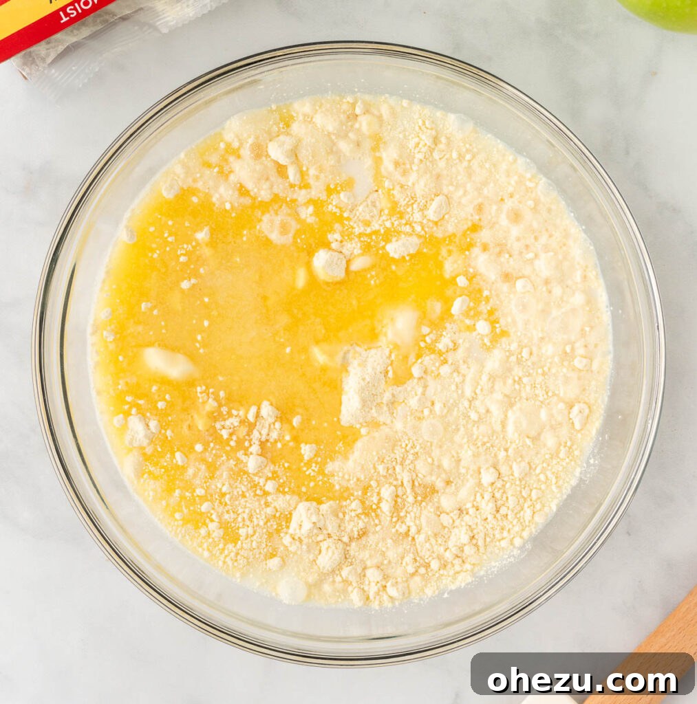 A bowl containing yellow cake mix, milk, and melted butter, ready to be combined for the cobbler topping.