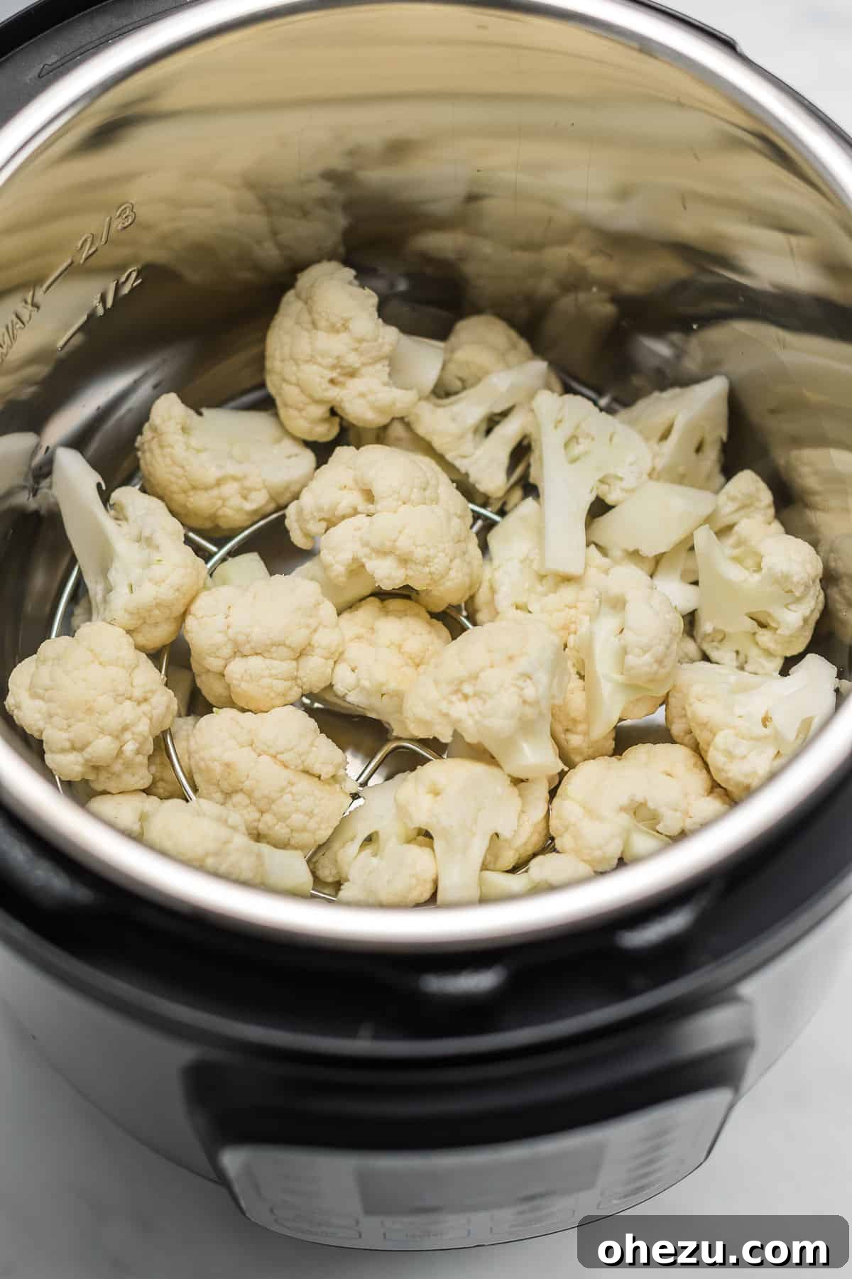 Raw cauliflower florets arranged inside an Instant Pot, ready for cooking.