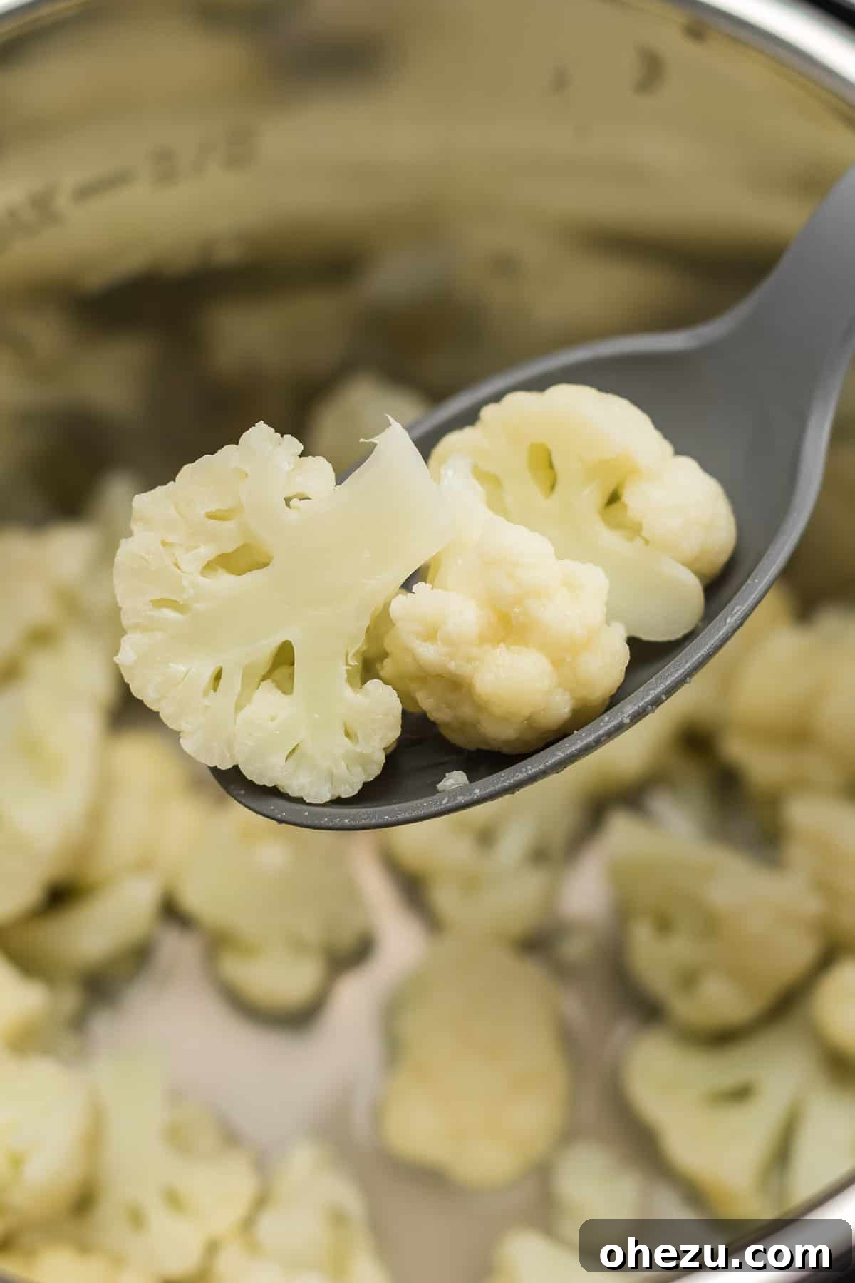 A spoon carefully removing steamed cauliflower florets from the Instant Pot.