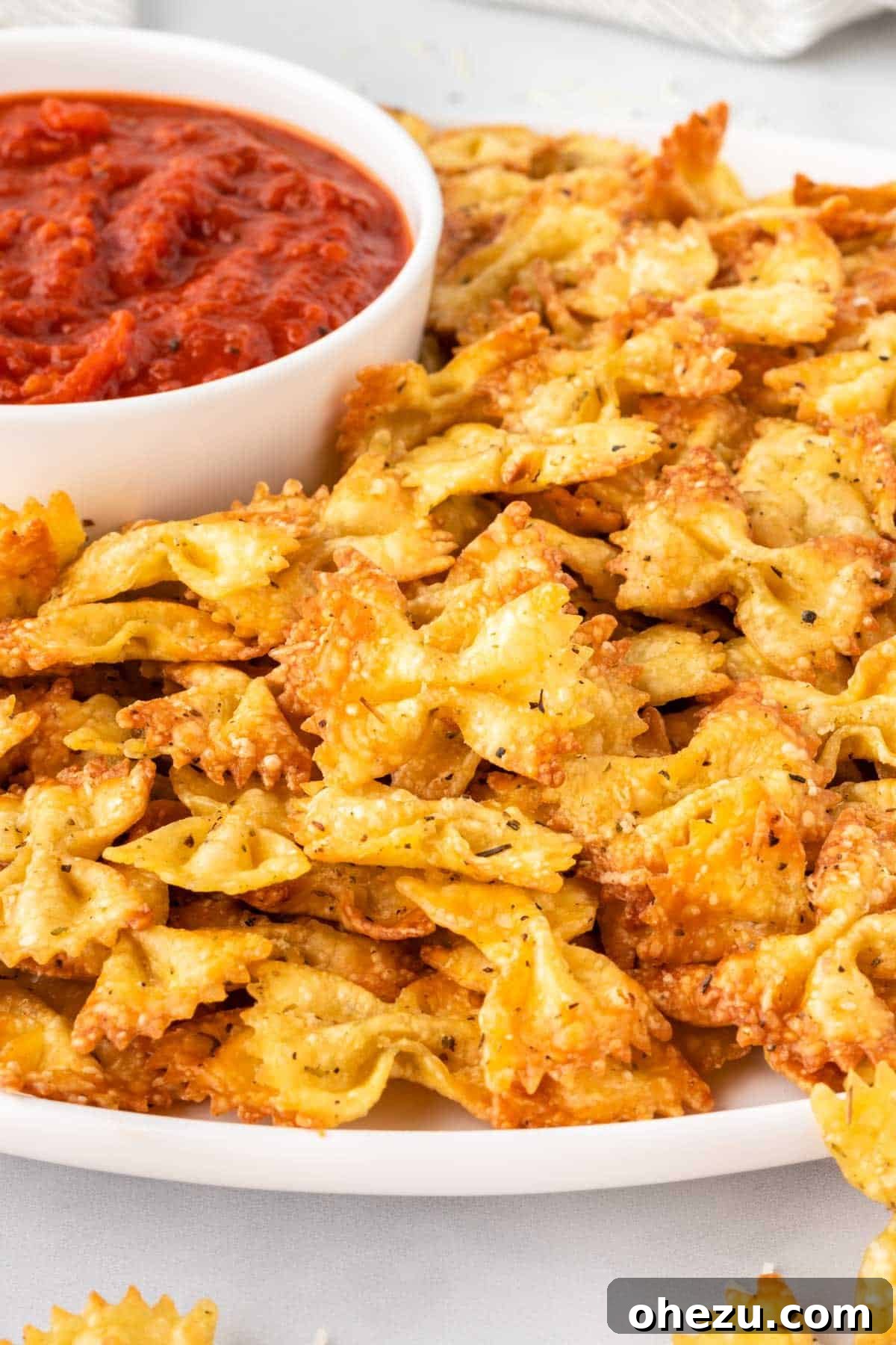 A plate of golden-brown pasta chips with a side of marinara for dipping