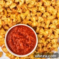 Crispy pasta chips served next to a bowl of marinara for dipping