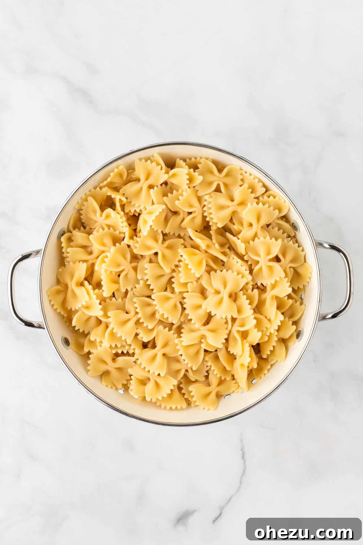 Cooked bowtie pasta draining in a strainer
