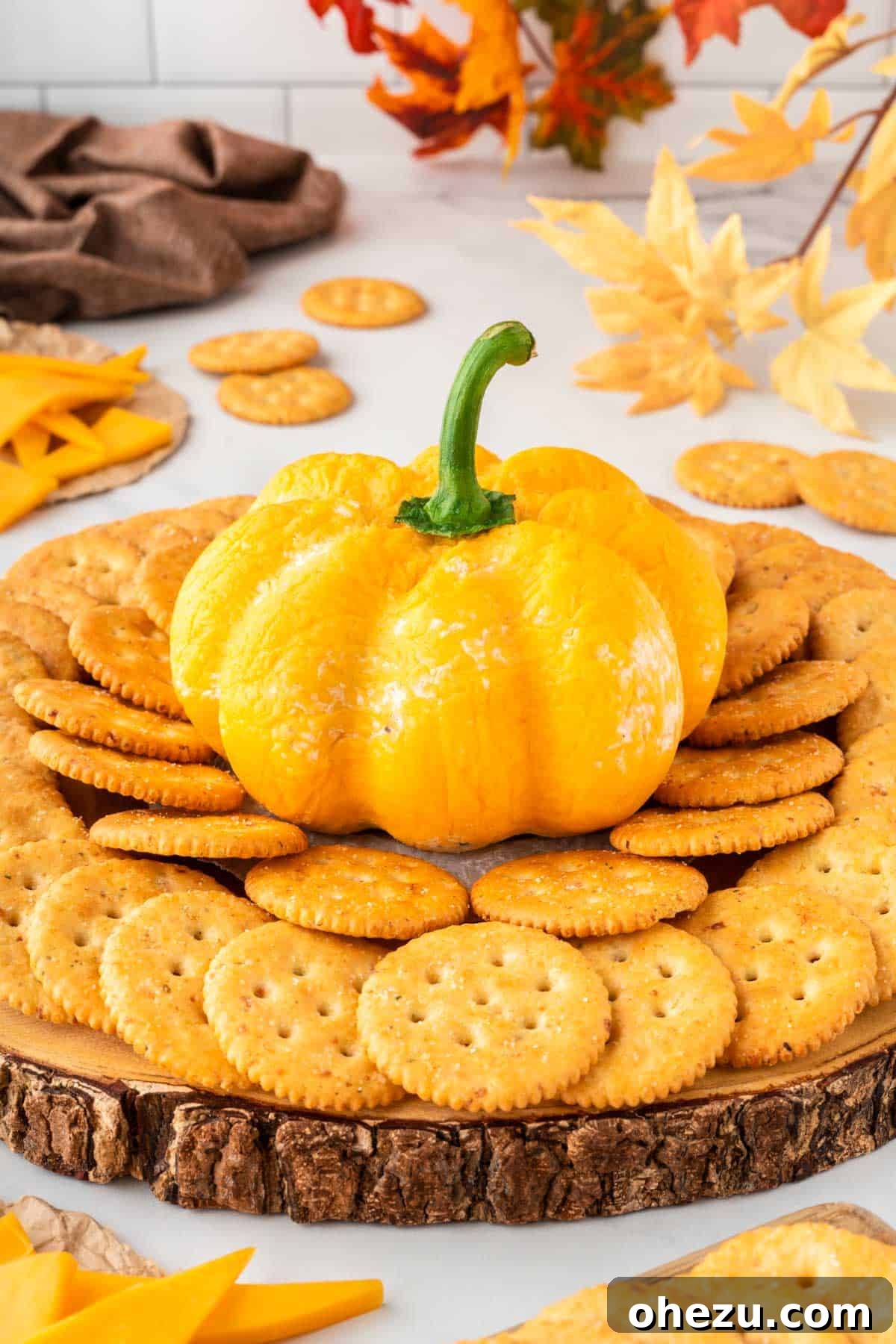pumpkin shaped cheese ball surrounded by crackers for dipping