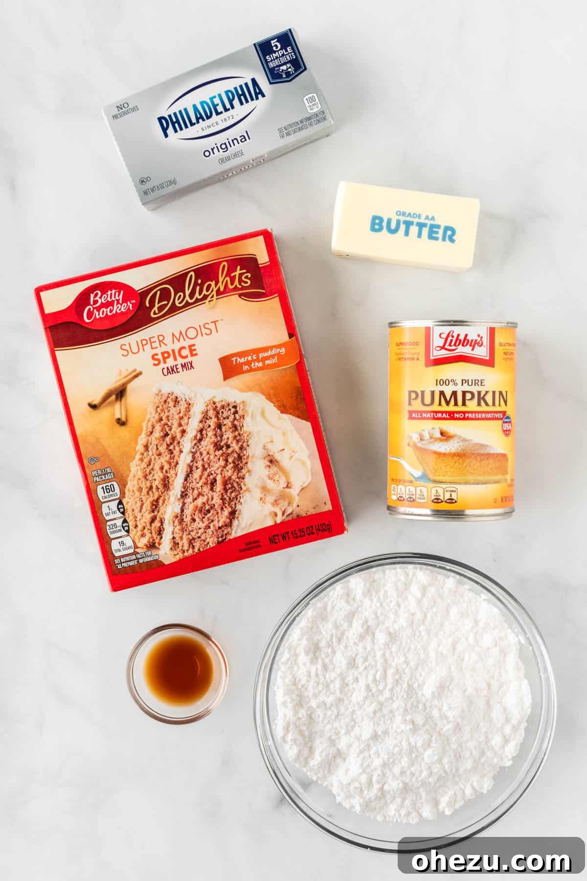 Effortless Fall Spiced Pumpkin Bars 4 All the simple ingredients laid out on a kitchen counter: a box of spice cake mix, a can of pumpkin puree, a block of cream cheese, butter, powdered sugar, and a bottle of vanilla extract.