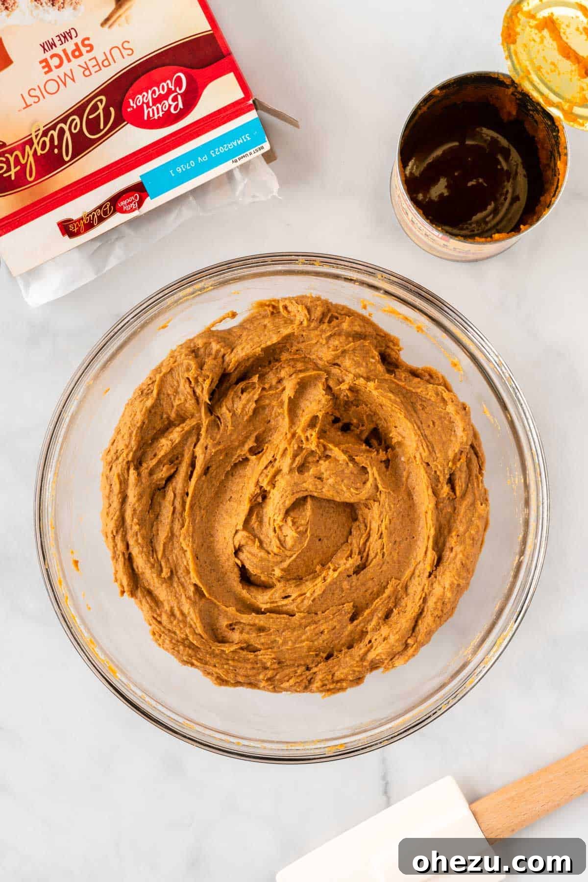 Effortless Fall Spiced Pumpkin Bars 6 The thick, orange pumpkin bar batter in a mixing bowl after the cake mix and pumpkin puree have been thoroughly combined, showing its uniform consistency.