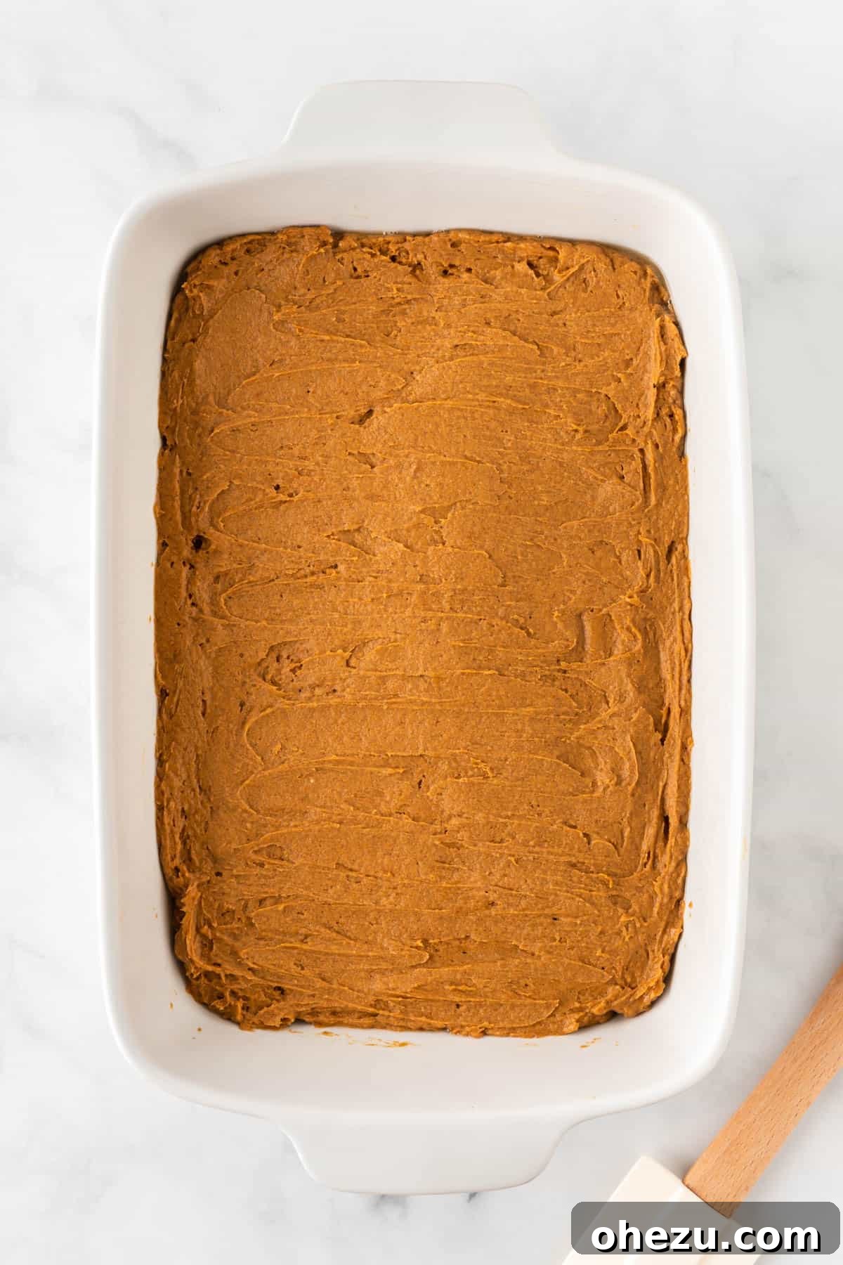 Effortless Fall Spiced Pumpkin Bars 7 The raw pumpkin batter evenly spread into a 9x13 inch glass baking dish, ready for baking.