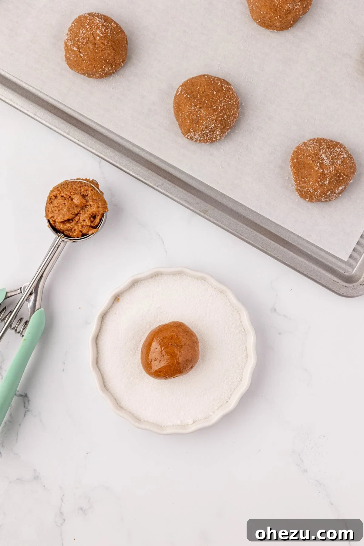 A hand gently rolling a ball of cake mix cookie dough into a bowl of coarse granulated sugar.