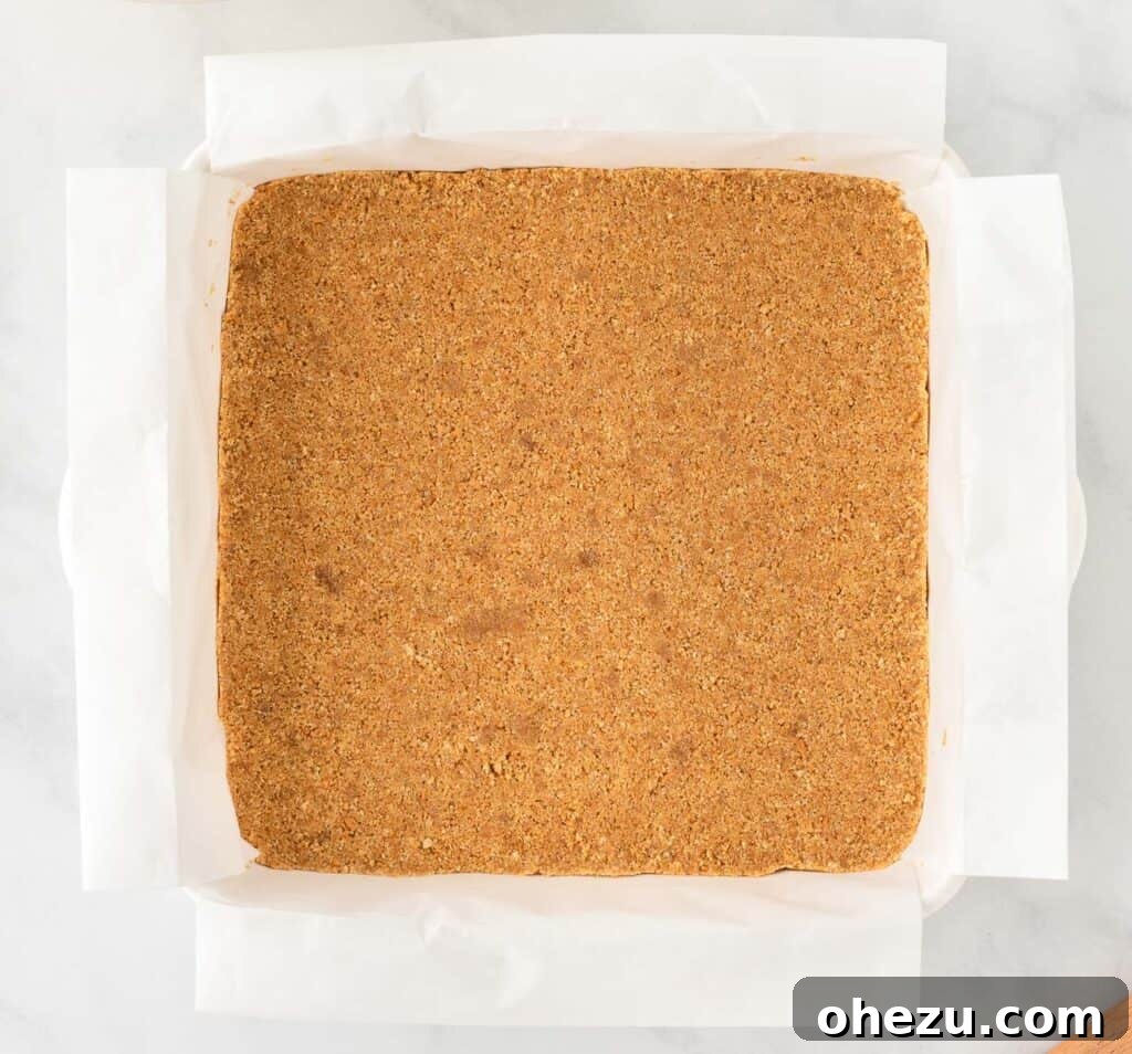 graham cracker crust pressed firmly into a parchment-lined pan