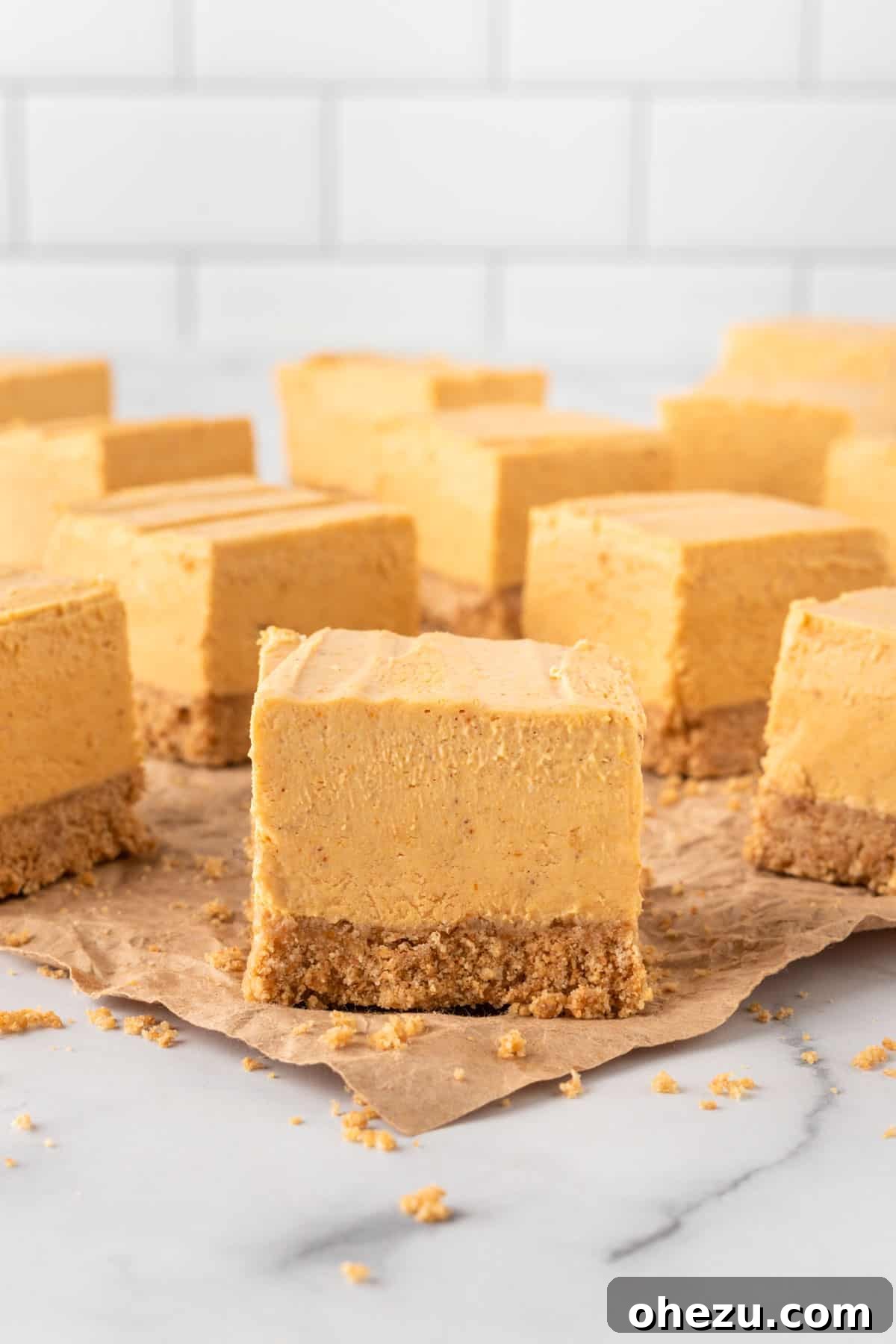 multiple squares of no bake pumpkin cheesecake bars stacked neatly on a white plate