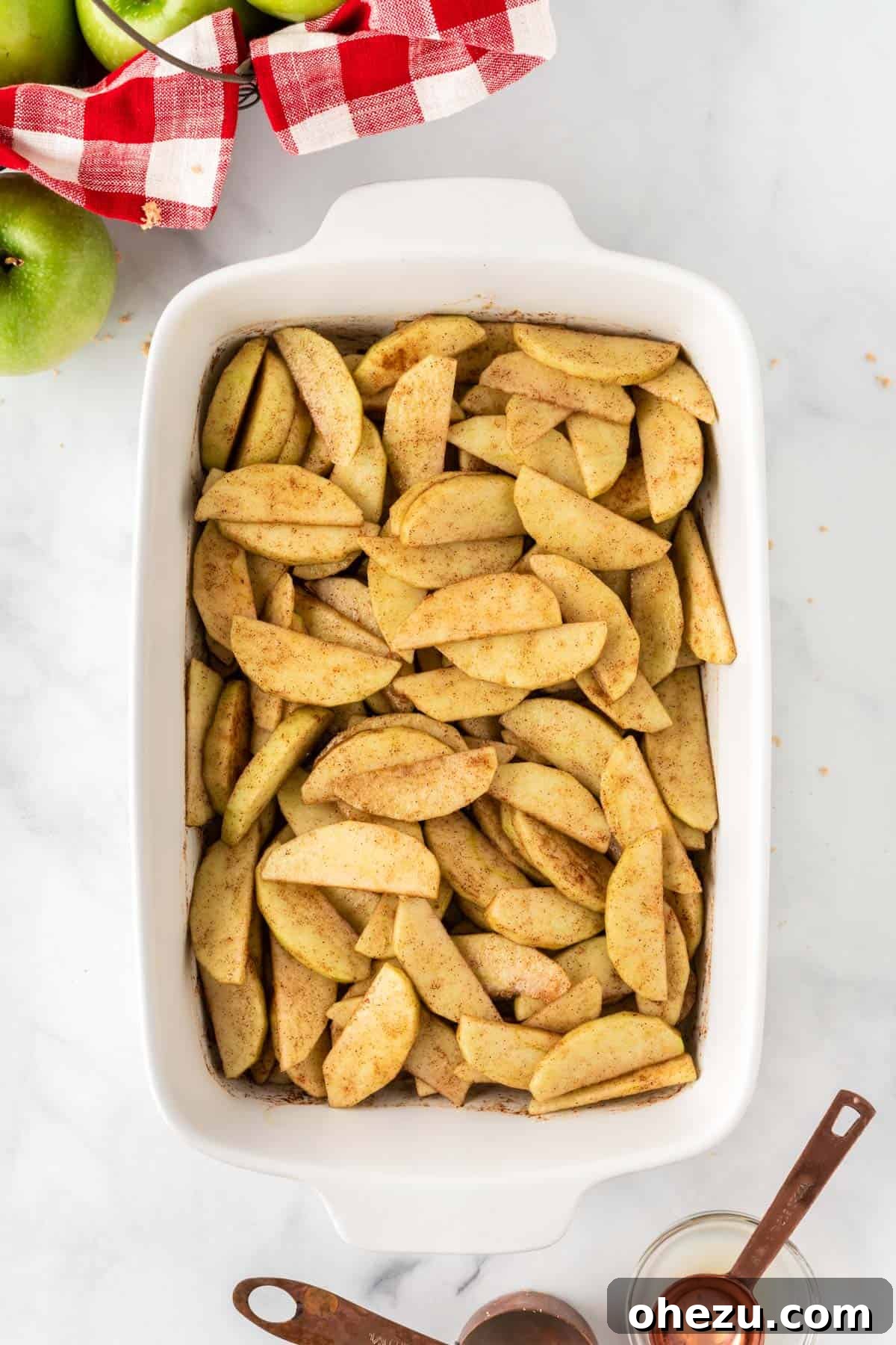 A wooden spoon gently tossing the apple slices with the spices, ensuring every piece is evenly coated and glistening with flavor.