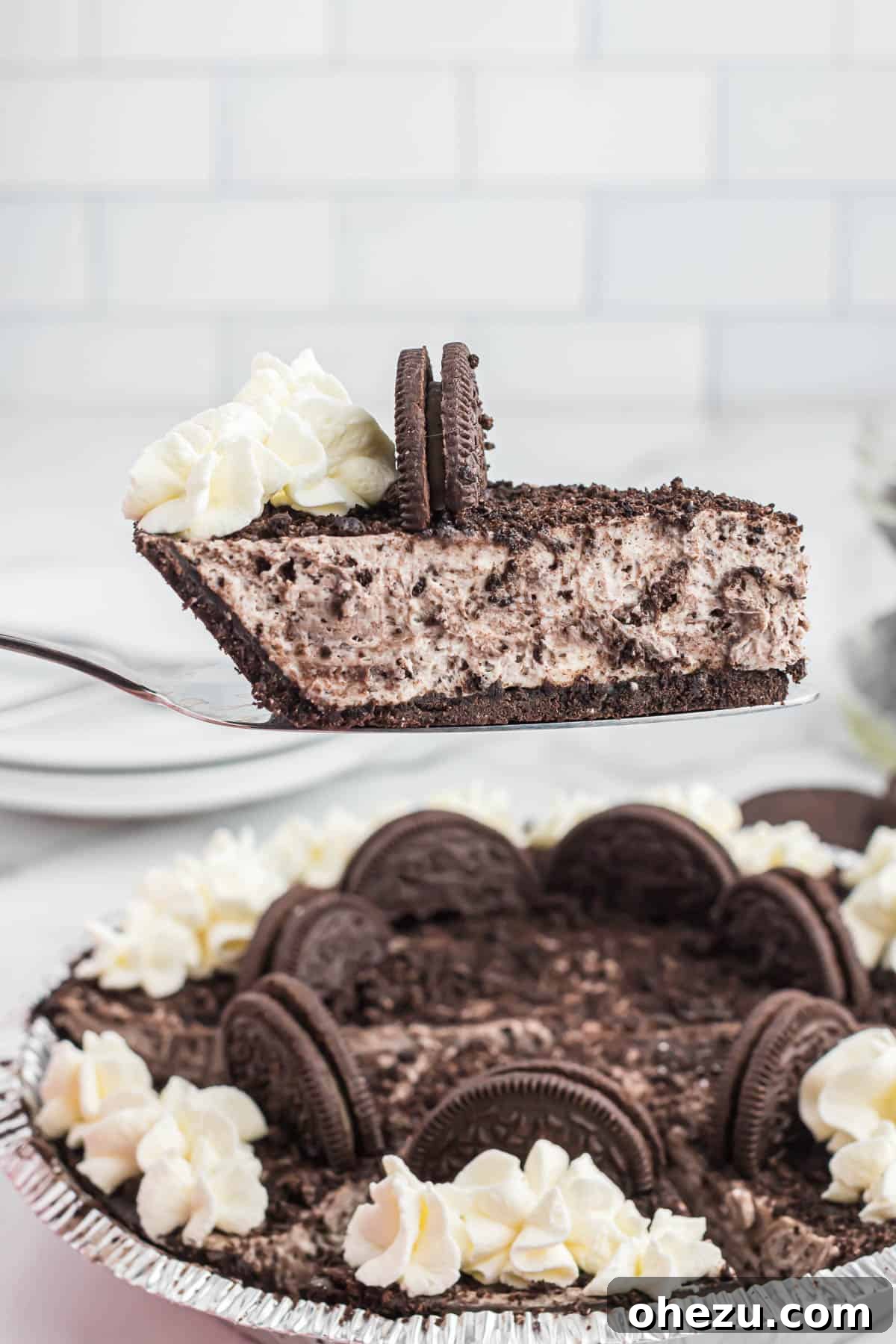 Decadent Oreo Delight 13 A hand gently taking a slice of No-Bake Oreo Pie from the full dish, showcasing its perfect texture and readiness to serve.