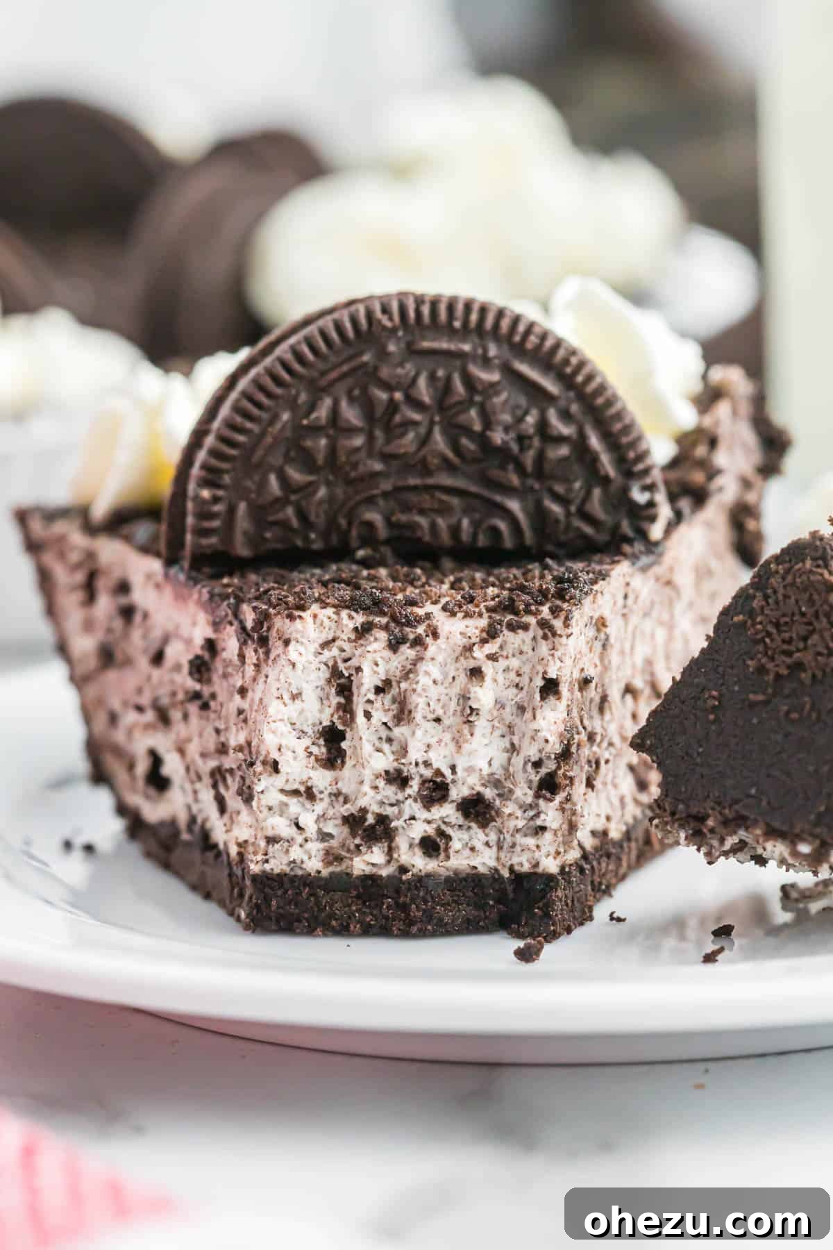 Decadent Oreo Delight 14 A close-up of a perfectly cut slice of No-Bake Oreo Pie on a white plate, emphasizing the creamy filling and crunchy crust texture.