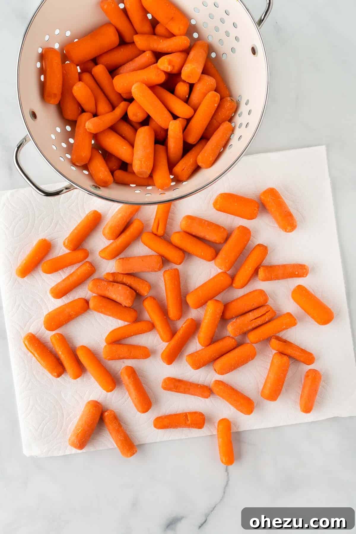 Baby carrots laid out on paper towels, being patted dry to remove excess moisture before cooking.