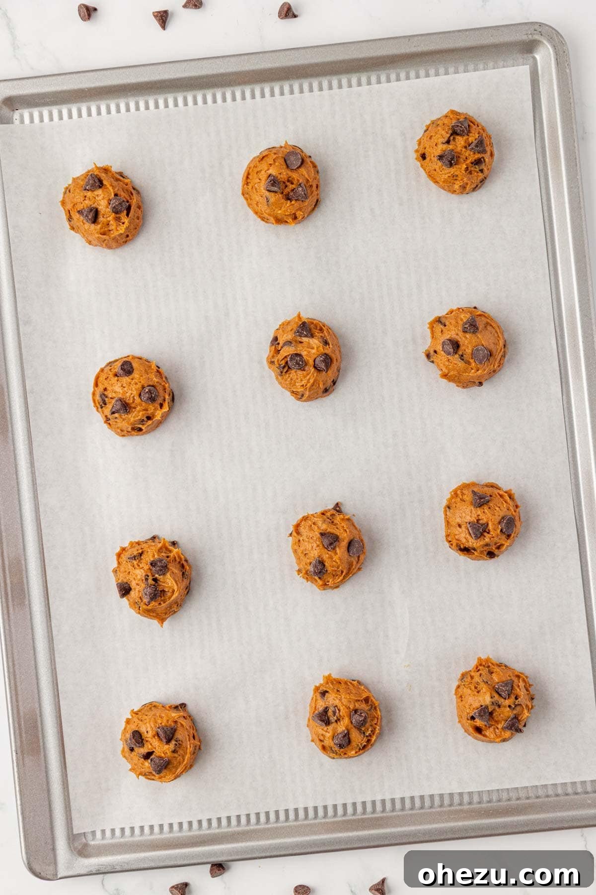 Portioned cake mix pumpkin cookie dough balls arranged on a baking sheet, ready to be baked.