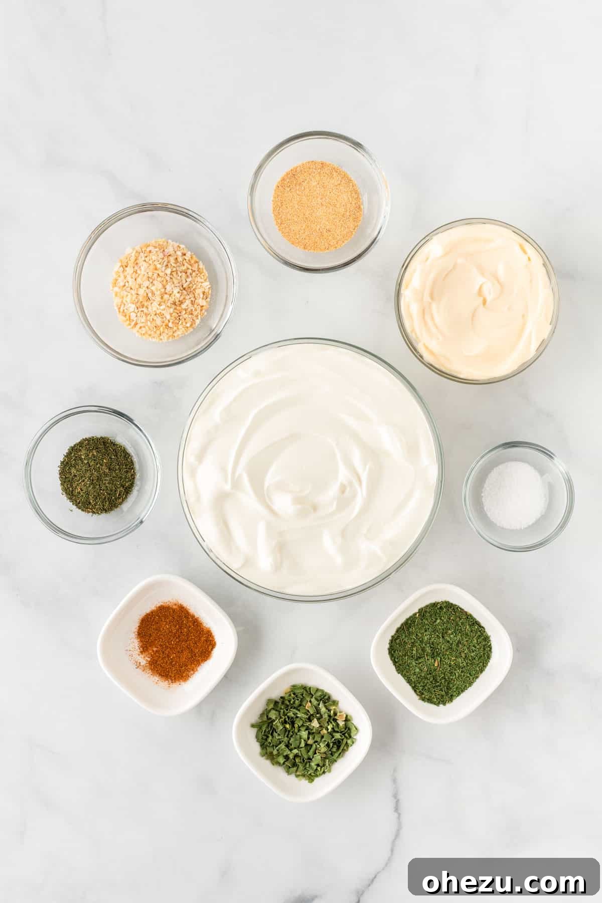 Garden Fresh Dip 4 A collection of ingredients laid out on a clean surface, including containers of sour cream and mayonnaise, and small bowls of various dried spices like garlic powder, dill, paprika, and dried minced onion, ready to be combined for the veggie dip.